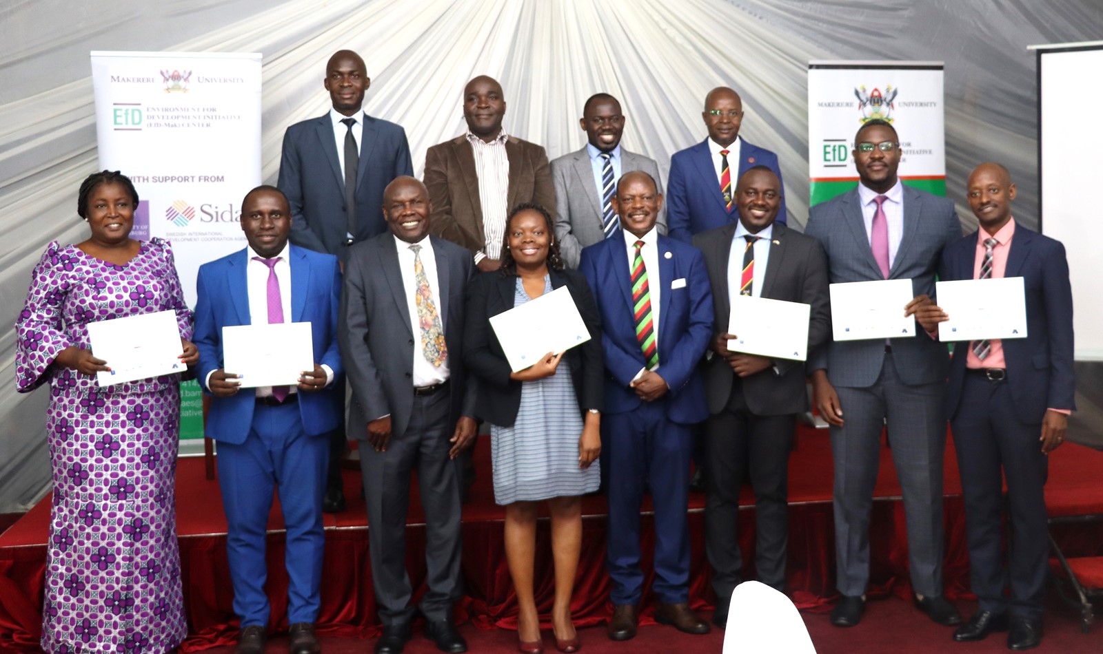 Graduands display their certificates in a group photo with Hon. Okaasai Opolot Sidronius (3rd Left), Prof. Barnabas Nawangwe (4th Right) and Prof. Edward Bbaale (Rear Right). EfD Uganda, Makerere University, Kampala Uganda, East Africa graduation of Third Cohort of the Inclusive Green Economy (IGE) Capacity Building Program Fellows, 7th August 2024, Kampala Sheraton Hotel.