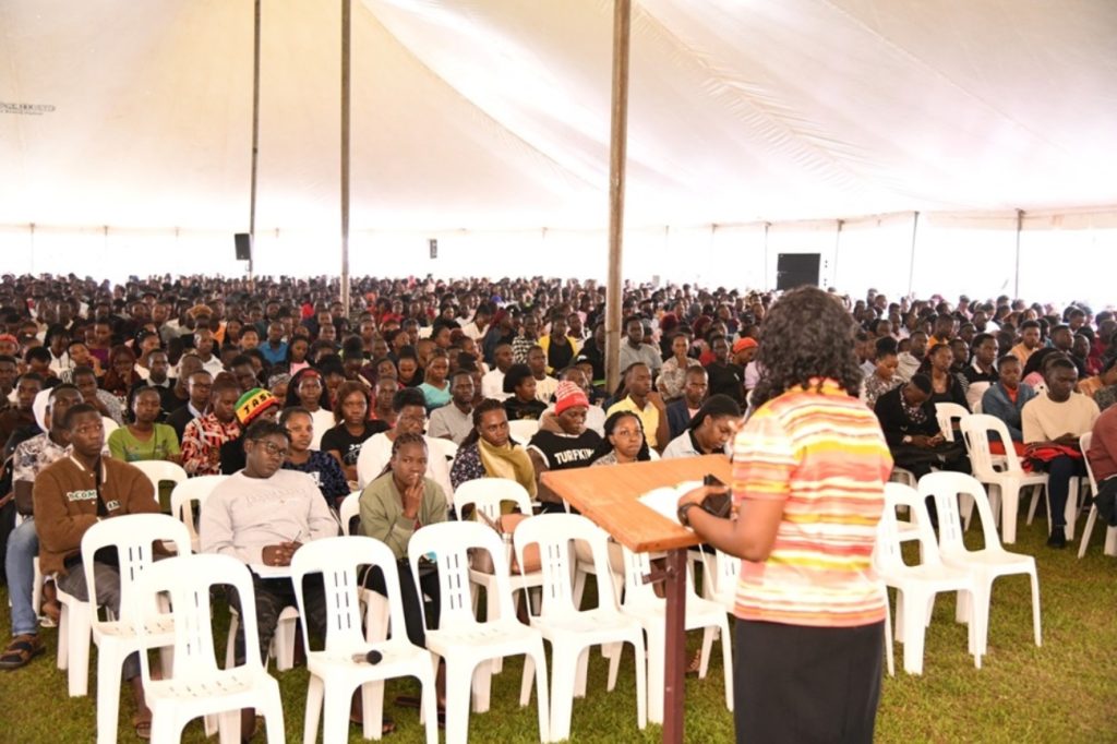 Students listen to Ms. Susan Mbabazi (back to camera). Freshers Orientation for Academic Year 2024/2025, 5th August 2024. Freedom Square, Makerere University, Kampala Uganda, East Africa.