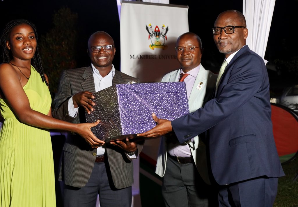 Prof. Bruno Yawe (Right) accompanied by a member of his family (Left) receives his gift from Prof. Edward Bbaale (2nd Right) and Prof. James Wokadala (2nd Left). College of Business and Management Sciences (CoBAMS) celebrates retiring staff and former leaders, 13th September 2024, Makerere University, Kampala Uganda, East Africa.