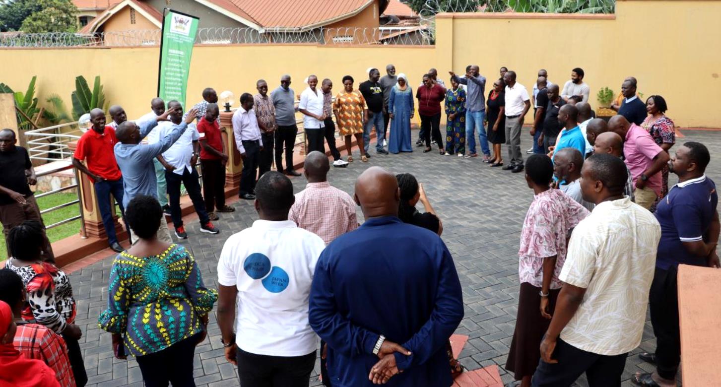 A Trainer, Mr. Ivan Kalema with staff outside the hotel conducting drills on leadership. Makerere University College of Humanities and Social Sciences (CHUSS) Staff Retreat, 1st-2nd November 2024, Nican Resort Hotel, Seguku Entebbe Road, Kampala Uganda, East Africa.