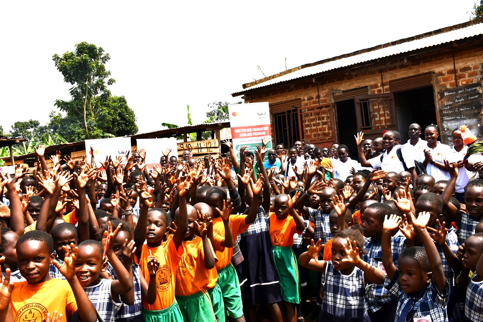 Pupils of Little Angels express their excitement during a group photo with the Scholars of Mastercard Foundation. Mastercard Foundation Scholars at Makerere University, Kampala during the Annual Scholars Day of Community Service at Little Angels Nursery and Primary School in Ntenjeru, Mukono District, and St. Charles Rwahunga, Nursery and Primary School in Kyegegwa District, Uganda, East Africa, 16th November 2024.