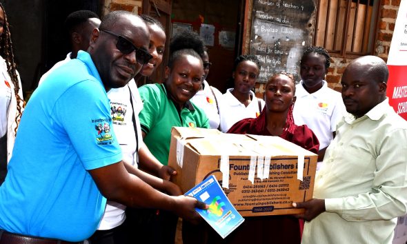 Mr. John Osuna, the Transition Lead, together with some of the Scholars, handing over the learning materials to the Chairperson of Parents' Association at Little Angels Primary School. Mastercard Foundation Scholars at Makerere University, Kampala during the Annual Scholars Day of Community Service at Little Angels Nursery and Primary School in Ntenjeru, Mukono District, and St. Charles Rwahunga, Nursery and Primary School in Kyegegwa District, Uganda, East Africa, 16th November 2024.