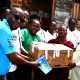 Mr. John Osuna, the Transition Lead, together with some of the Scholars, handing over the learning materials to the Chairperson of Parents' Association at Little Angels Primary School. Mastercard Foundation Scholars at Makerere University, Kampala during the Annual Scholars Day of Community Service at Little Angels Nursery and Primary School in Ntenjeru, Mukono District, and St. Charles Rwahunga, Nursery and Primary School in Kyegegwa District, Uganda, East Africa, 16th November 2024.