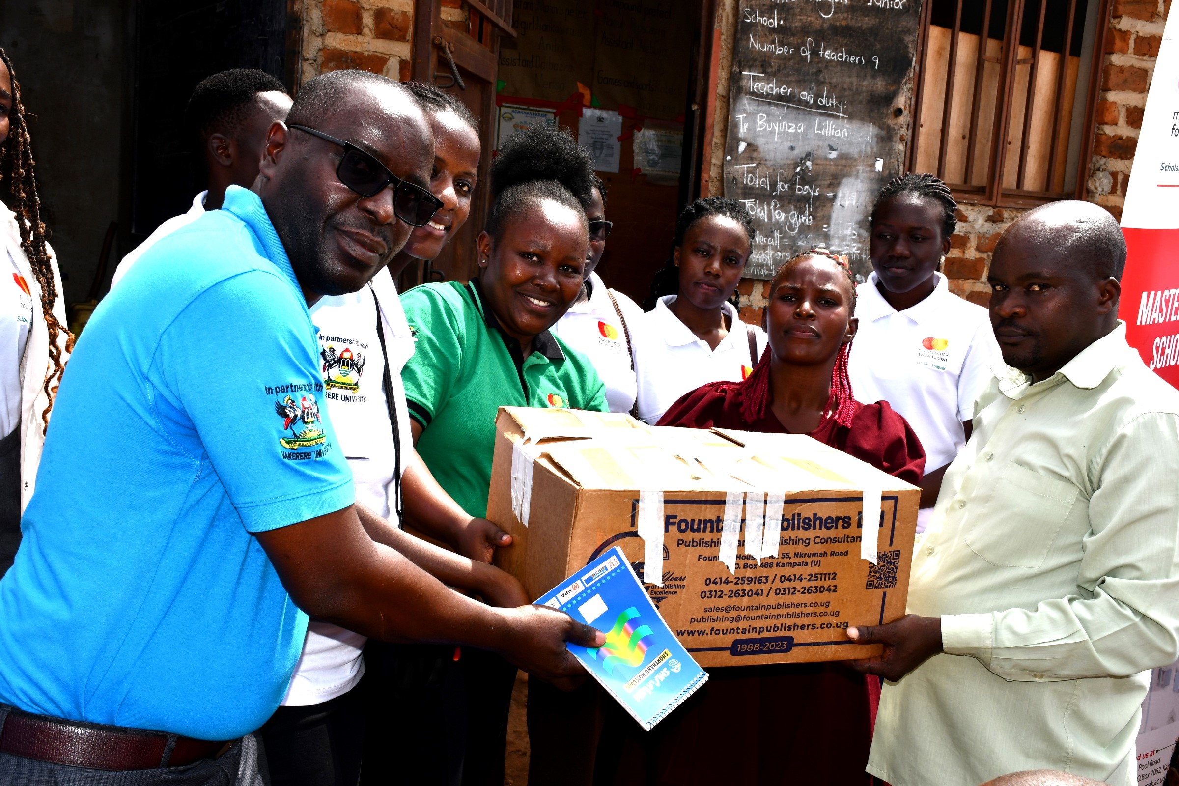 Mr. John Osuna, the Transition Lead, together with some of the Scholars, handing over the learning materials to the Chairperson of Parents' Association at Little Angels Primary School. Mastercard Foundation Scholars at Makerere University, Kampala during the Annual Scholars Day of Community Service at Little Angels Nursery and Primary School in Ntenjeru, Mukono District, and St. Charles Rwahunga, Nursery and Primary School in Kyegegwa District, Uganda, East Africa, 16th November 2024.