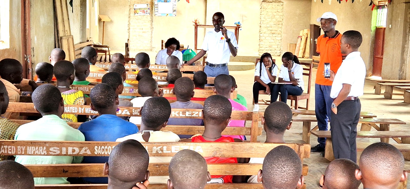 Mr. Ddumba Nelson, the Scholars' Council representative, speaking to the Pupils of St. Charles Rwahunga Primamary School. Mastercard Foundation Scholars at Makerere University, Kampala during the Annual Scholars Day of Community Service at Little Angels Nursery and Primary School in Ntenjeru, Mukono District, and St. Charles Rwahunga, Nursery and Primary School in Kyegegwa District, Uganda, East Africa, 16th November 2024.