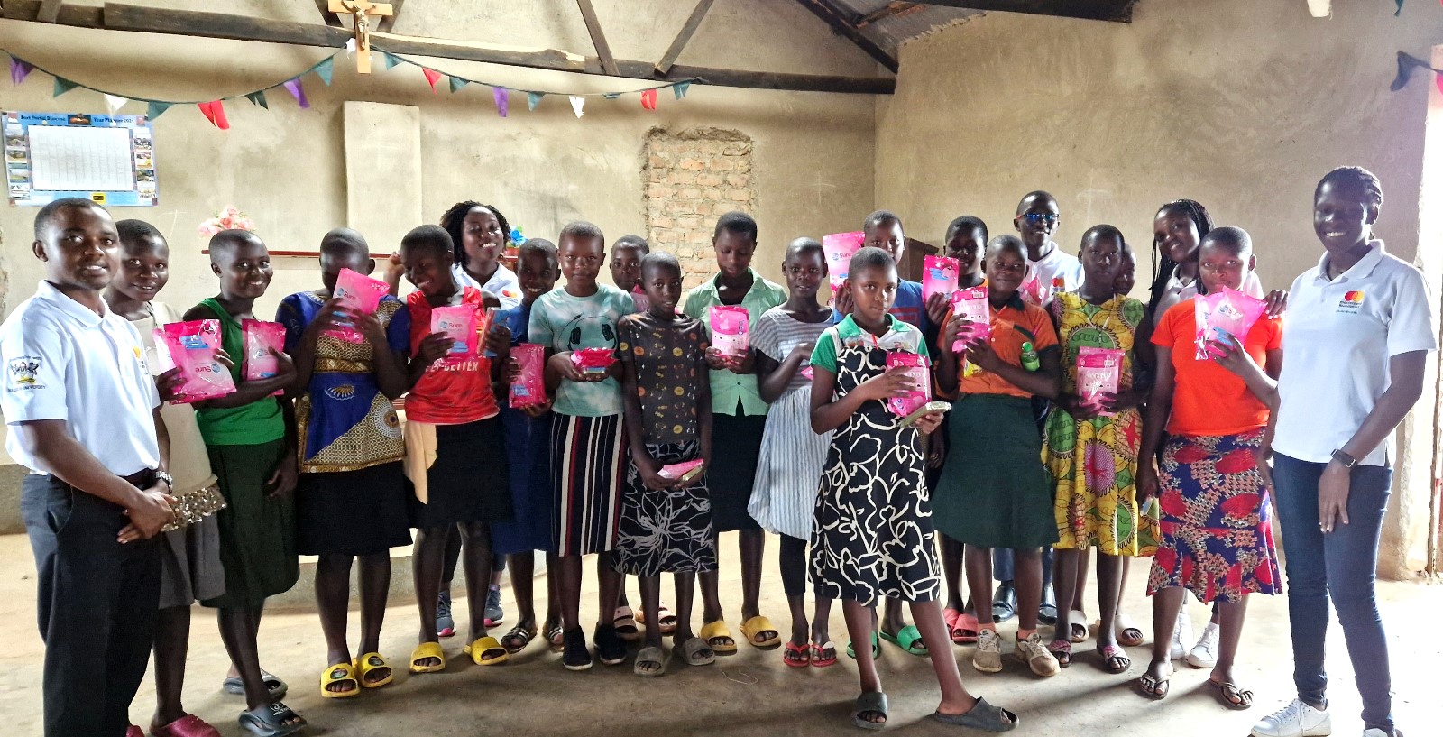 A cross-section of schoolgirls of St. Charles Rwahunga Primary School pose in a photo with sanitary towels donated by Scholars of Mastercard Foundation. Mastercard Foundation Scholars at Makerere University, Kampala during the Annual Scholars Day of Community Service at Little Angels Nursery and Primary School in Ntenjeru, Mukono District, and St. Charles Rwahunga, Nursery and Primary School in Kyegegwa District, Uganda, East Africa, 16th November 2024.