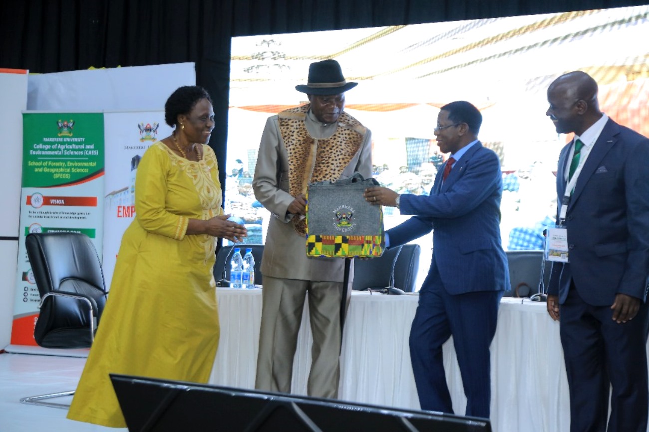 Prof. Buyinza Mukadasi (2nd R) presents an assortment of Mak Souvenirs to Umukhukha Jude Mike Mudoma (2nd L) as Hon. Beatrice Atim Anywar (L) and Assoc. Prof. Yazidhi Bamutaze (R) witness. College of Agricultural and Environmental Sciences (CAES), Makerere University in partnership with International Geographical Union (IGU) Commission of Biogeography and Biodiversity, the IGU Commission on African Studies, Uganda Geographical Association, and the International Association of Landscape Ecology (IALE) African Chapter, 3rd International Conference on Geographical Science for Resilient Communities, Ecosystems and Livelihoods under Global Environmental Change (GORILLA), Day 1, 4th December 2024, Hotel Africana, Kampala Uganda, East Africa.