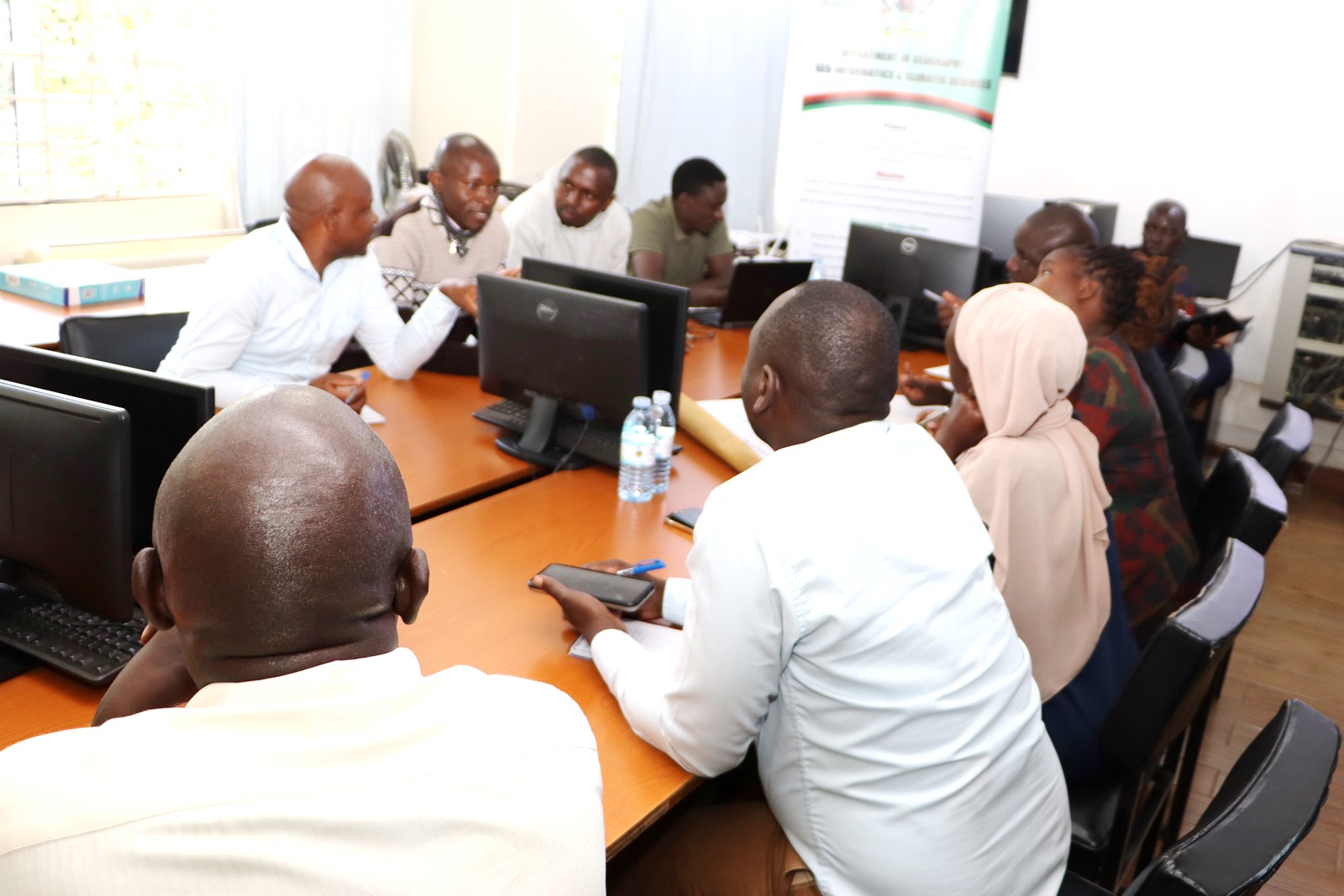 Group two members discussing. Department of Geography, Geo-informatics, and Climatic Sciences at Makerere University, in collaboration with the Department of Geography at Kyambogo University, workshop to disseminate research findings from three climate adaptation and mitigation projects funded by the Regional Universities Forum for Capacity Building in Agriculture (RUFORUM), RAINCA, WASCAL, Akademiya2063, and the Carnegie Corporation of New York under the CECAP Program, 19th December 2024, GIS Lab, CoCIS Block A, Makerere University, Kampala Uganda, East Africa.