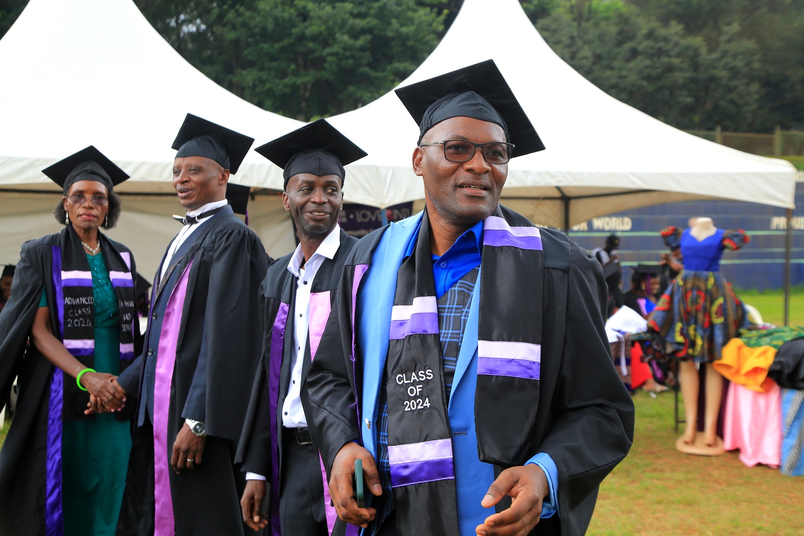 Some of the graduating candidates with their creations in the background. 240 students graduated with certificates and diplomas from the College of Education and External Studies (CEES) under the Love Binti Program, which offers training in fashion design and hairdressing, 13th December 2024, Impis Rugby Grounds, Makerere University, Kampala Uganda, East Africa.