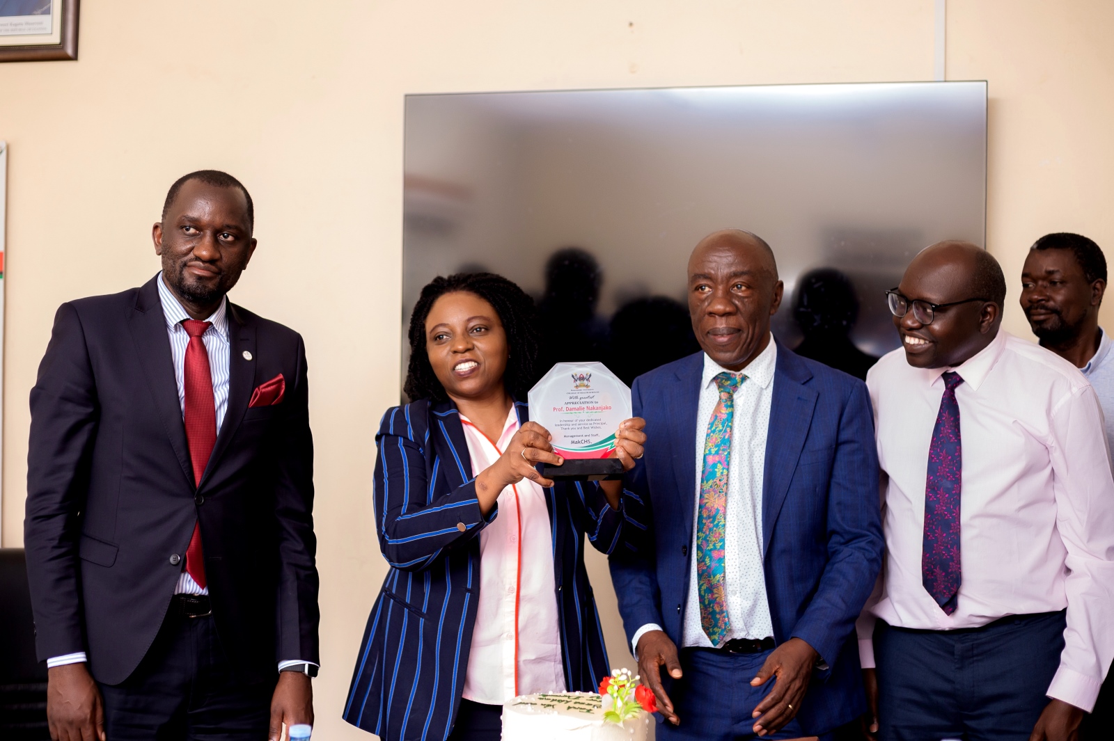 Prof. Damalie Nakanjako (2nd Left) shows of her plaque as Ag. DVCFA-Prof. Henry Alinaitwe (2nd Right), Deputy US-Mr. Simon Kizito (Left), Dr. David Patrick Kateete (Right) and Dr. Richard Idro (2nd Right) witness. Handover of Principal Office by Prof. Damalie Nakanjako to Assoc. Prof. Bruce Kirenga, 2nd December 2024, College Boardroom, College of Health Sciences (CHS), Makerere University, New Mulago Hospital Complex, Kampala Uganda, East Africa.