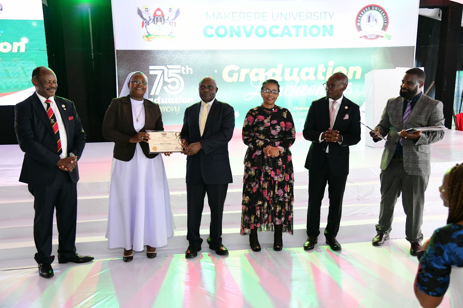 Hon. Dr. Crispus Kiyonga (3rd L) presents the best lecturer award to Dr. Sr. Namaganda Justine (2nd L) as Left to Right: Prof. Barnabas Nawangwe, VC UNISA-Prof. Puleng LenkaBula, Chair Convocation-Mr. George Turyamureeba Mugabi and Assoc. Prof. Robert Wamala. 75th Graduation Ceremony, Day 1, CoCIS, CEES, CoVAB and School of Law. 13th January 2025, Freedom Square, Makerere University, Kampala Uganda, East Africa.