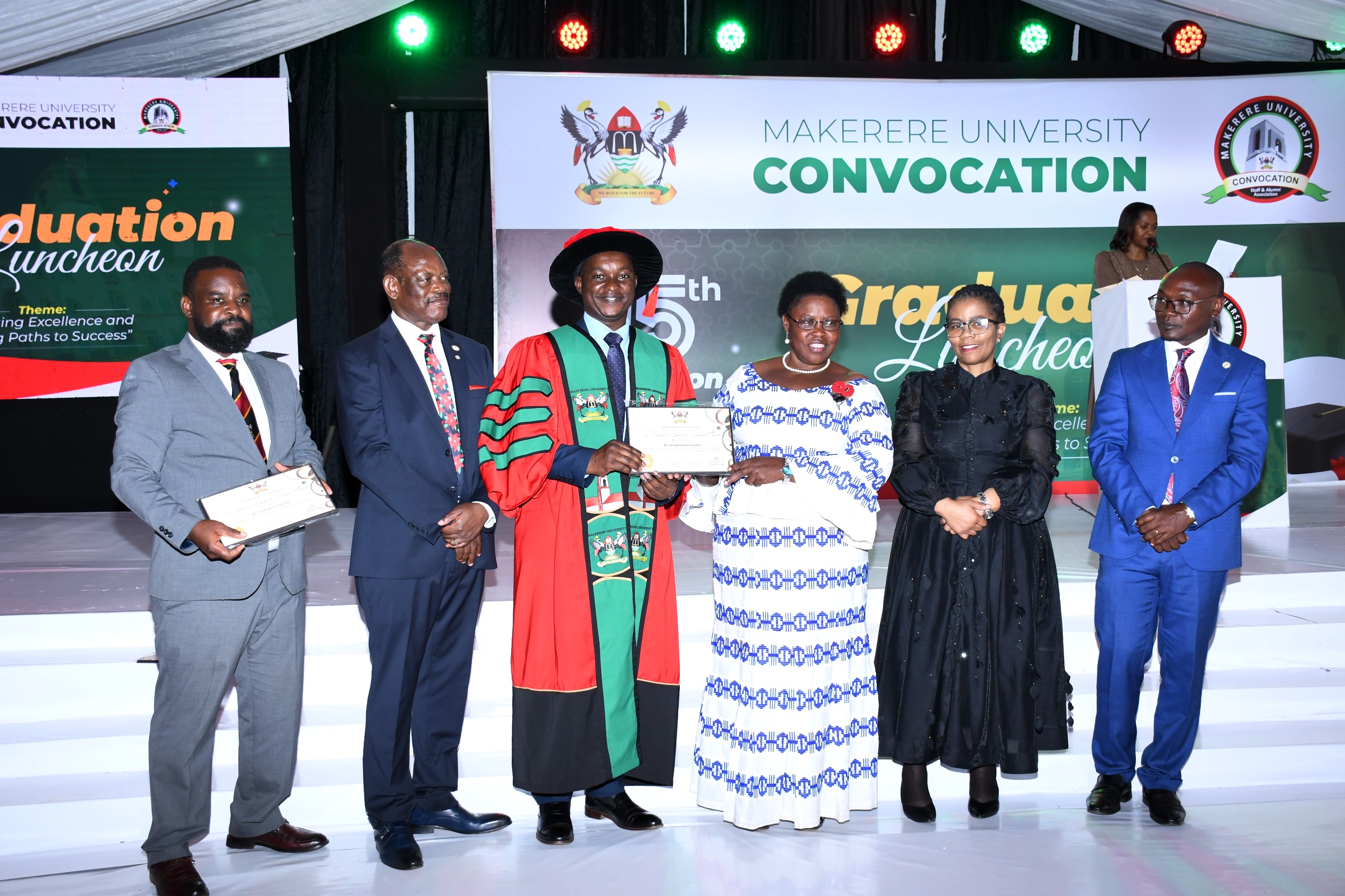 Hon. Dr. Joyce Moriku Kaducu (3rd R) presents the Mid-Career Award to Dr. Ssendawula Kasimu (3rd L) during the Convocation Luncheon. 75th Graduation Ceremony, Day 2, CoBAMS, CHS and CoNAS. 14th January 2025, Research, Teaching, Students Excellence Awards, Edge Road, Makerere University, Kampala Uganda, East Africa.