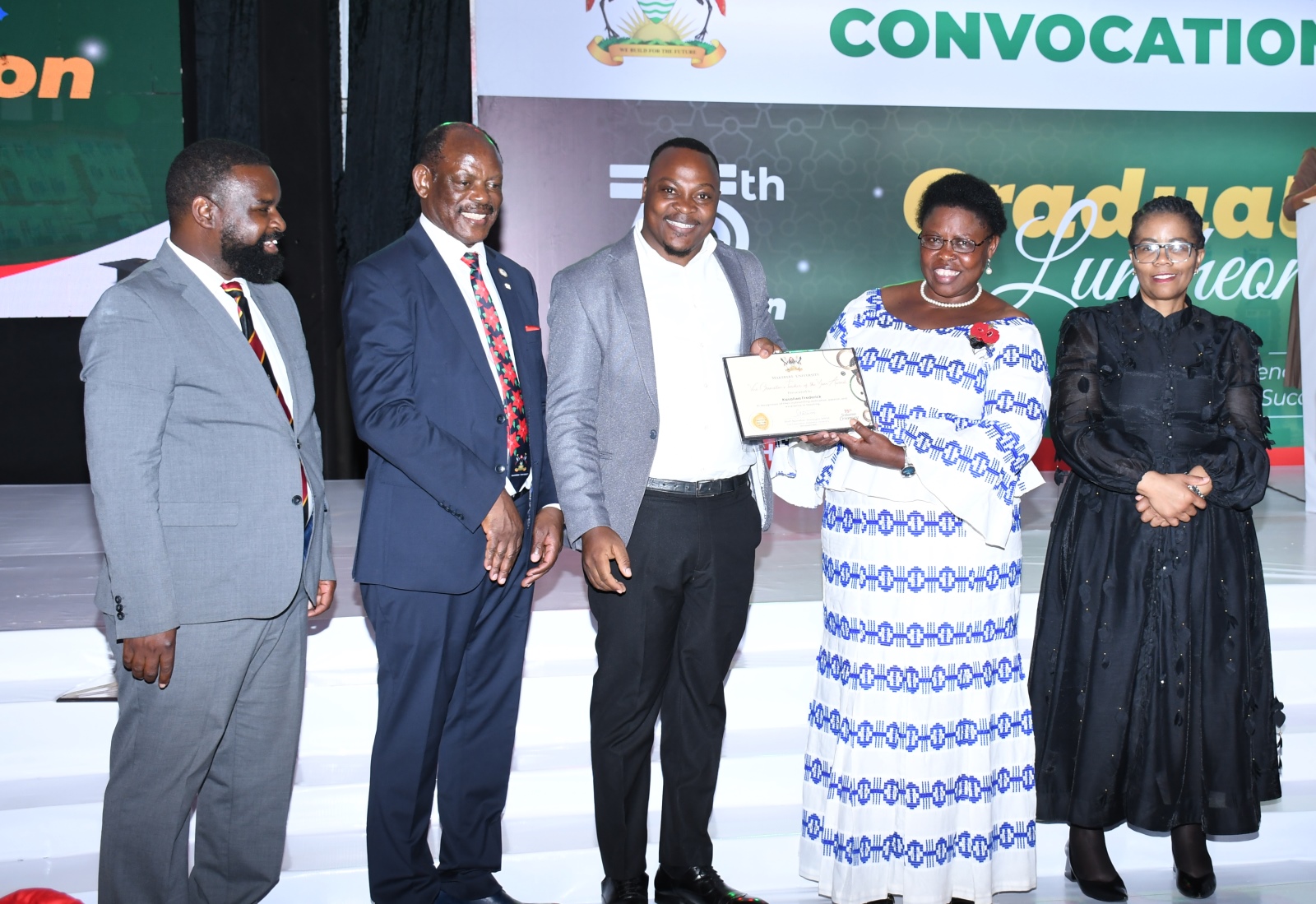 Hon. Dr. Joyce Moriku Kaducu (2nd R) presents the Teacher of the Year Award to Fredrick Kasalirwe (C) during the Convocation Luncheon. 75th Graduation Ceremony, Day 2, CoBAMS, CHS and CoNAS. 14th January 2025, Research, Teaching, Students Excellence Awards, Edge Road, Makerere University, Kampala Uganda, East Africa.