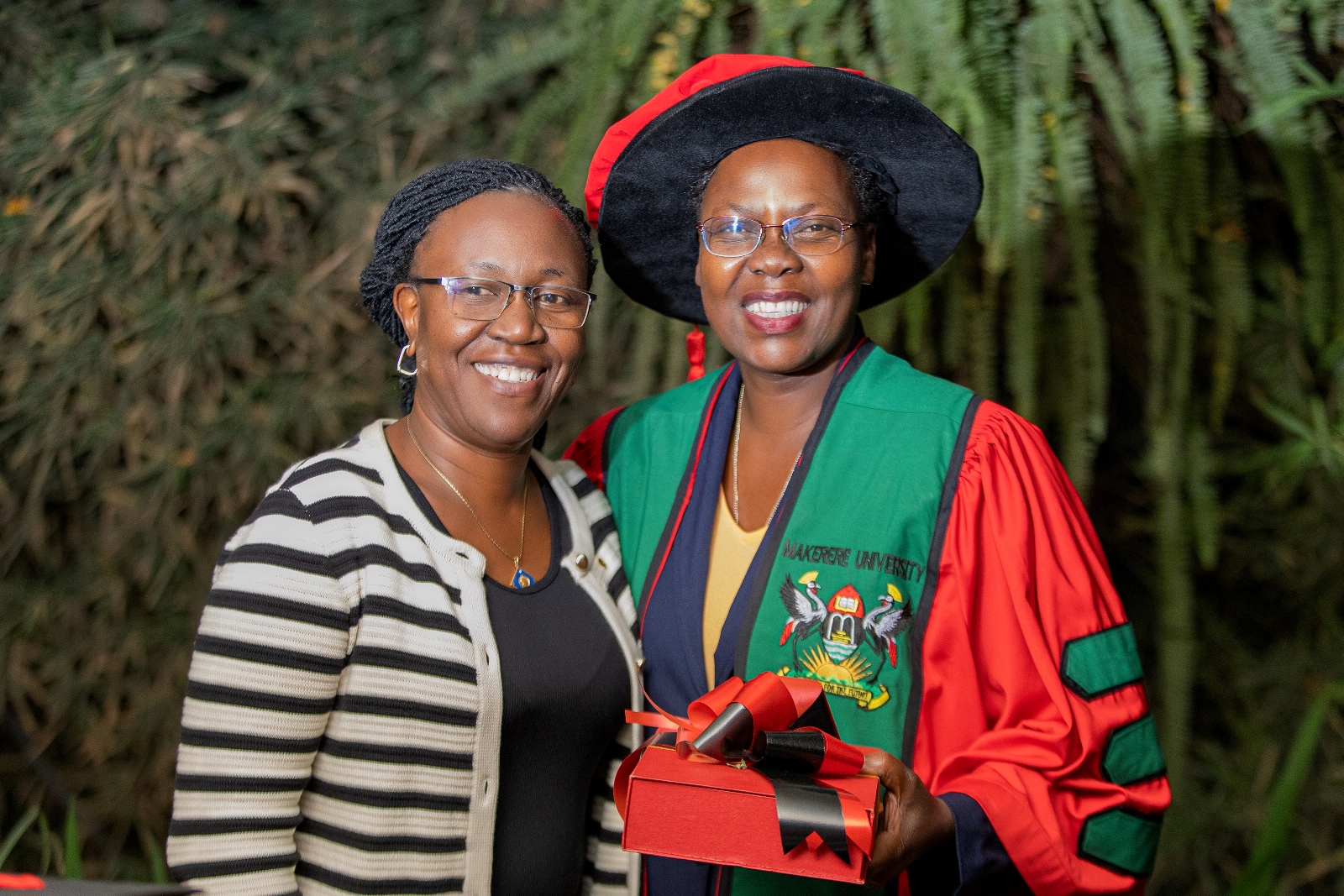 Dr. Christine K. Nalwadda, a Senior Lecturer and Head, Department of Community Health and Behavioural Sciences of the School of Public Health hands a plaque to Dr. Roselline Achola to congratulate her on her PhD. 75th Graduation Ceremony, Day 2, CoBAMS, CHS and CoNAS. 14th January 2025, Freedom Square, Makerere University, Kampala Uganda, East Africa.