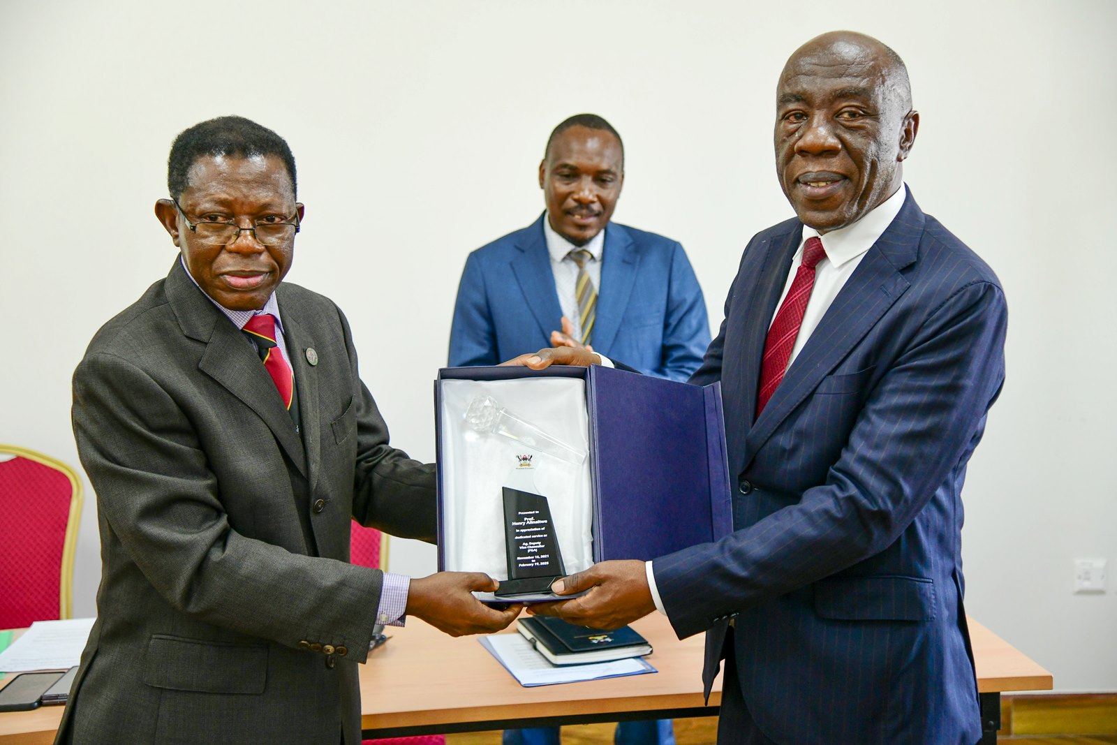 Prof. Buyinza Mukadasi (L) presents a plaque of appreciation from the University Management to Prof. Henry Alinaitwe (R) as Prof. Winston Tumps Ireeta (C) witnesses. Prof. Henry Alinaitwe officially hands over Office of Deputy Vice Chancellor (Finance and Administration)-DVCFA to Prof. Winston Tumps Ireeta, 20th February 2025, Main Building, Makerere University, Kampala Uganda, East Africa.