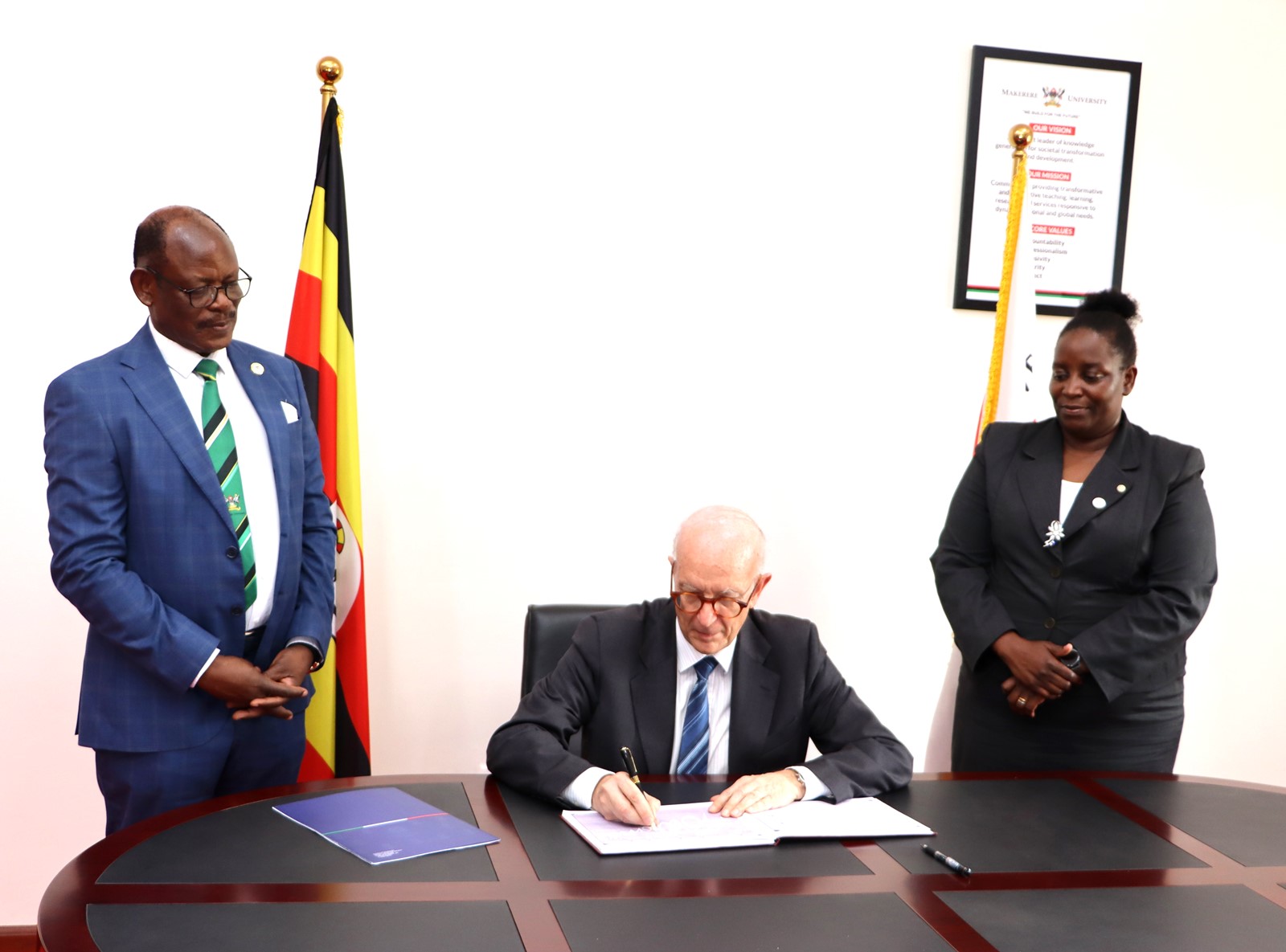 The Ambassador signs the Visitors' book flanked by the Vice Chancellor and Principal CHUSS. Makerere University, in collaboration with the University of Turin and the Italian Embassy in Kampala, marked four decades of academic and cultural partnership with a landmark photographic exhibition titled "Connecting Cultures: The Italian Ethnological Mission in the Great Lakes Region" 16th May 2025, Arts Quadrangle, College of Humanities and Social Sciences (CHUSS), Uganda, East Africa.