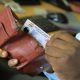 A man reaches for the Uganda National ID from his wallet. New study, “Understanding the Benefits, Costs, and Challenges of the National Identification System in Uganda,” published in Digital Society, for every US$1 invested in the NID system, the return on investment is US$1.35, led by Roy William Mayega from Makerere University School of Public Health’s Resilient Africa Network (MakSPH-RAN), Kampala, Uganda, East Africa.