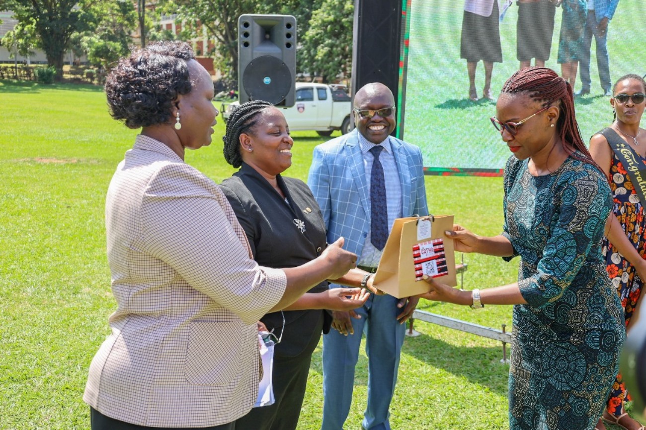 Prof. Helen Nambalirwa Nkabala handing over a gift to a female participant. Science of Designing, Adaptation, and Implementation of Evidence-Based Parenting Interventions 12-week course, Child Health and Development Centre (CHDC), College of Health Sciences (CHS) graduation presided over by The Iteso Cultural Leader, His Highness Emorimor Papa Paul Sande Emolot, 11th June 2025, Freedom Square, Makerere University, Kampala Uganda, East Africa.