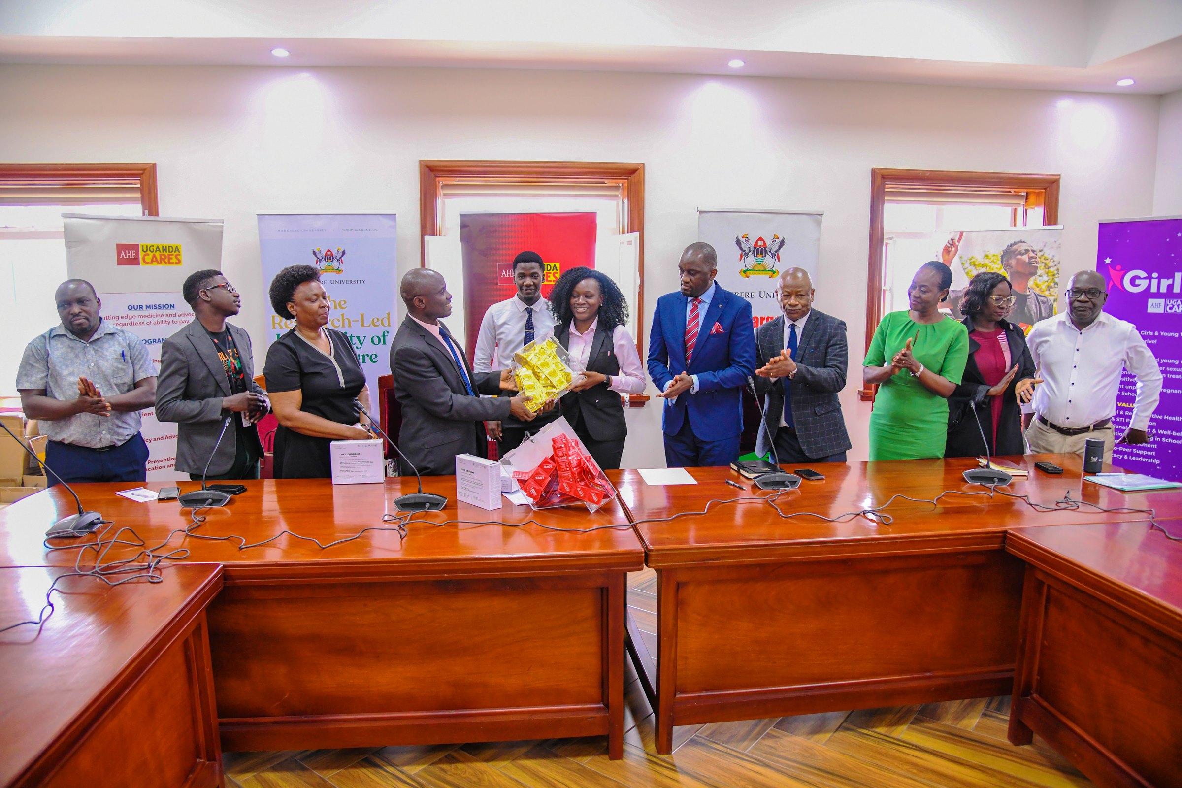 National Medical Director-AHF Uganda Cares, Dr. Lubanga Augustine hands over condom dispensers and condoms to the 91st Vice Guild President-H.E. Kadondi Gracious as officials witness on 30th July 2025. Makerere University and the Aids Healthcare Foundation (AHF) Uganda Cares meeting to collaborate on HIV/AIDS prevention and care services for the University’s student population, 30th July 2025, Main Building, Kampala Uganda, East Africa.
