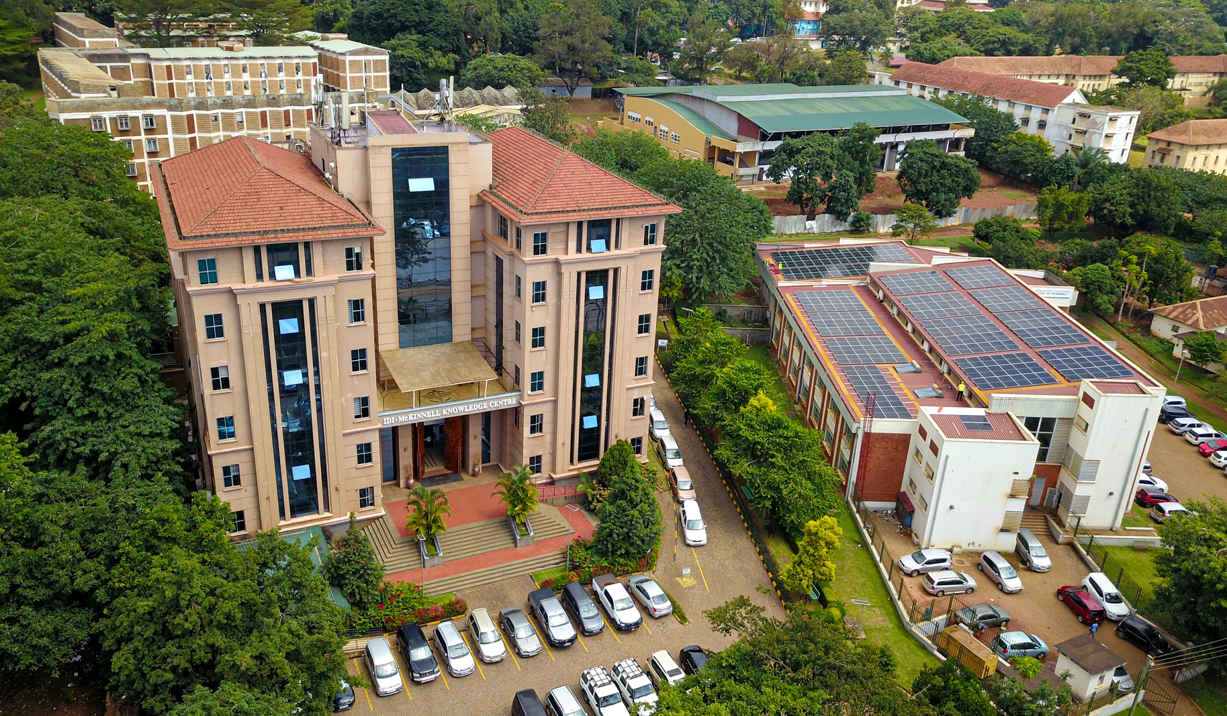 An elevated shot of the IDI-McKinnell Knowledge Centre (Left) and the Department of Pharmacy Building (Right) with the array of solar panels. Vice Chancellor, Prof. Barnabas Nawangwe inaugurated the Infectious Diseases Institute (IDI) at Makerere University's ground-breaking 384kWp solar-powered electricity grid, Africa’s largest campus-based solar system, July 24, 2024, Kampala Uganda, East Africa.