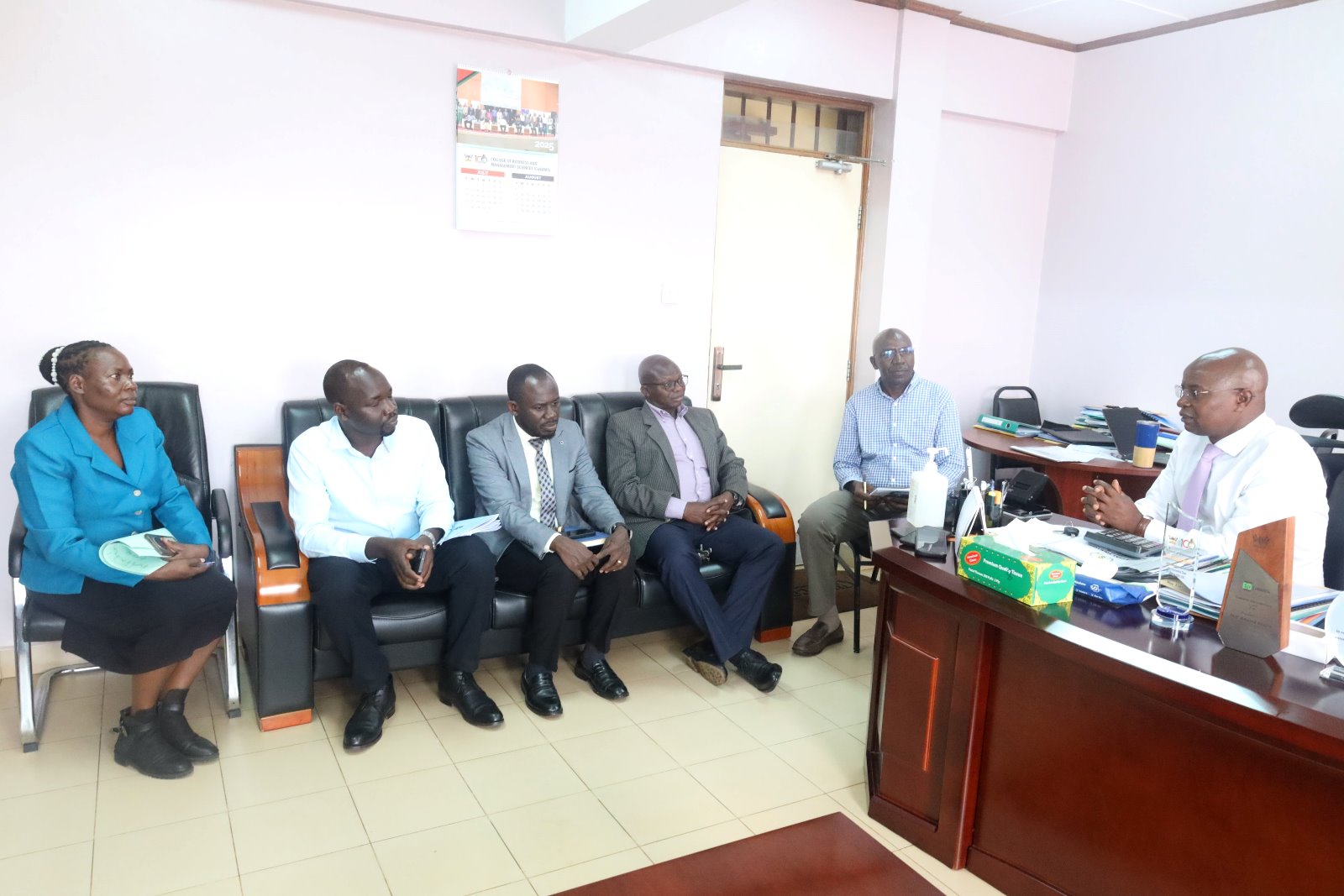 L-R: Mrs. Juliet Mirembe Ssewankambo, Dr. Christopher Alioni, Dr. Peter Babyenda, Assoc. Prof. James Wokadala, Mr. Peter Mubiru, and Prof. Edward Bbaale interact. Prof. Edward Bbaale, the Principal of the College of Business and Management Sciences (CoBAMS) endorsed the newly-established College SACCO by enrolling as a member on 22nd July 2025, Makerere University, Kampala Uganda, East Africa.