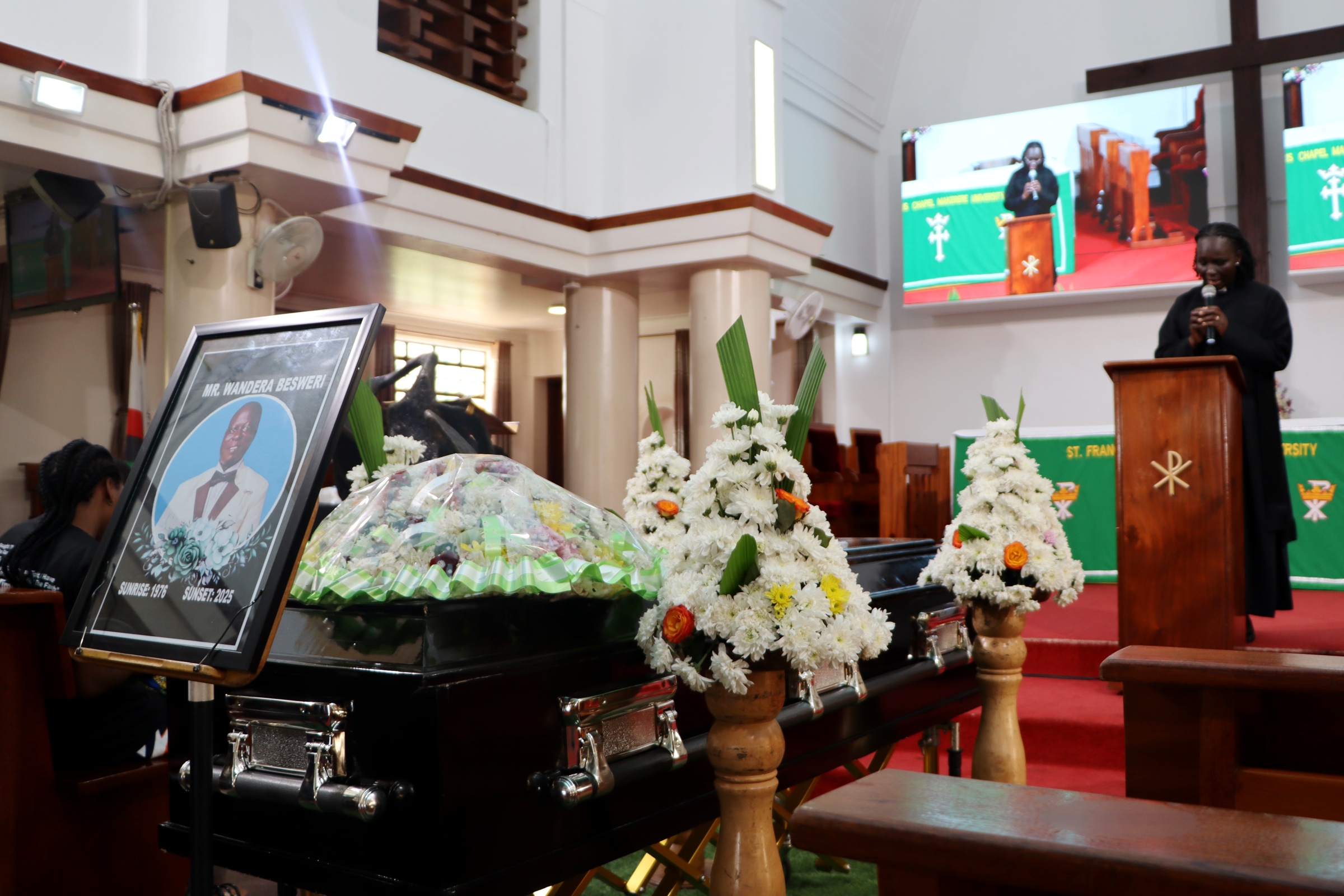 Mr. Besweri Wandera's casket in St. Francis Chapel as Rev. Scovia Kumakech leads the service. Funeral Service in honour Mr. Besweri Wandera, Assistant Lecturer, Department of Sports Science, College of Natural Sciences (CoNAS), 24th July 2025, St. Francis Chapel, Makerere University, Kampala Uganda, East Africa.