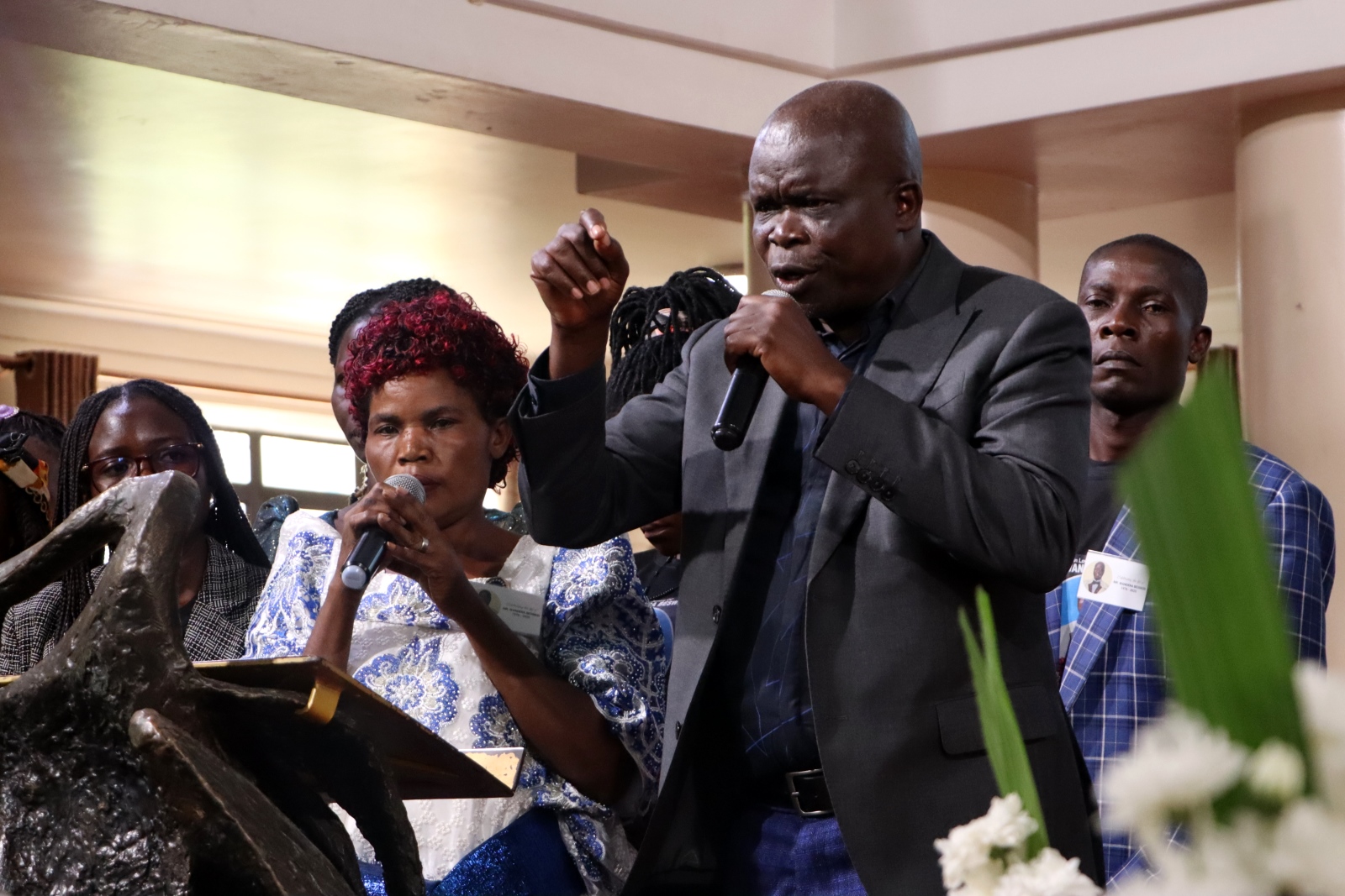 Mr. Wandera's widow, Everlyn Hayoko Nanyanga (in white gomesi) makes her remarks as Mr. Isaac Egesa Obuli (Right) interprets. Funeral Service in honour Mr. Besweri Wandera, Assistant Lecturer, Department of Sports Science, College of Natural Sciences (CoNAS), 24th July 2025, St. Francis Chapel, Makerere University, Kampala Uganda, East Africa.