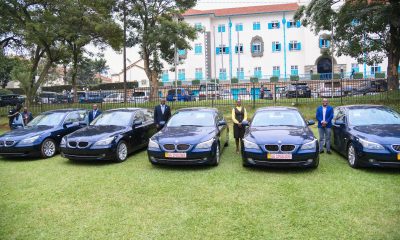 Officials stand besides five limousines recieved by Makerere University