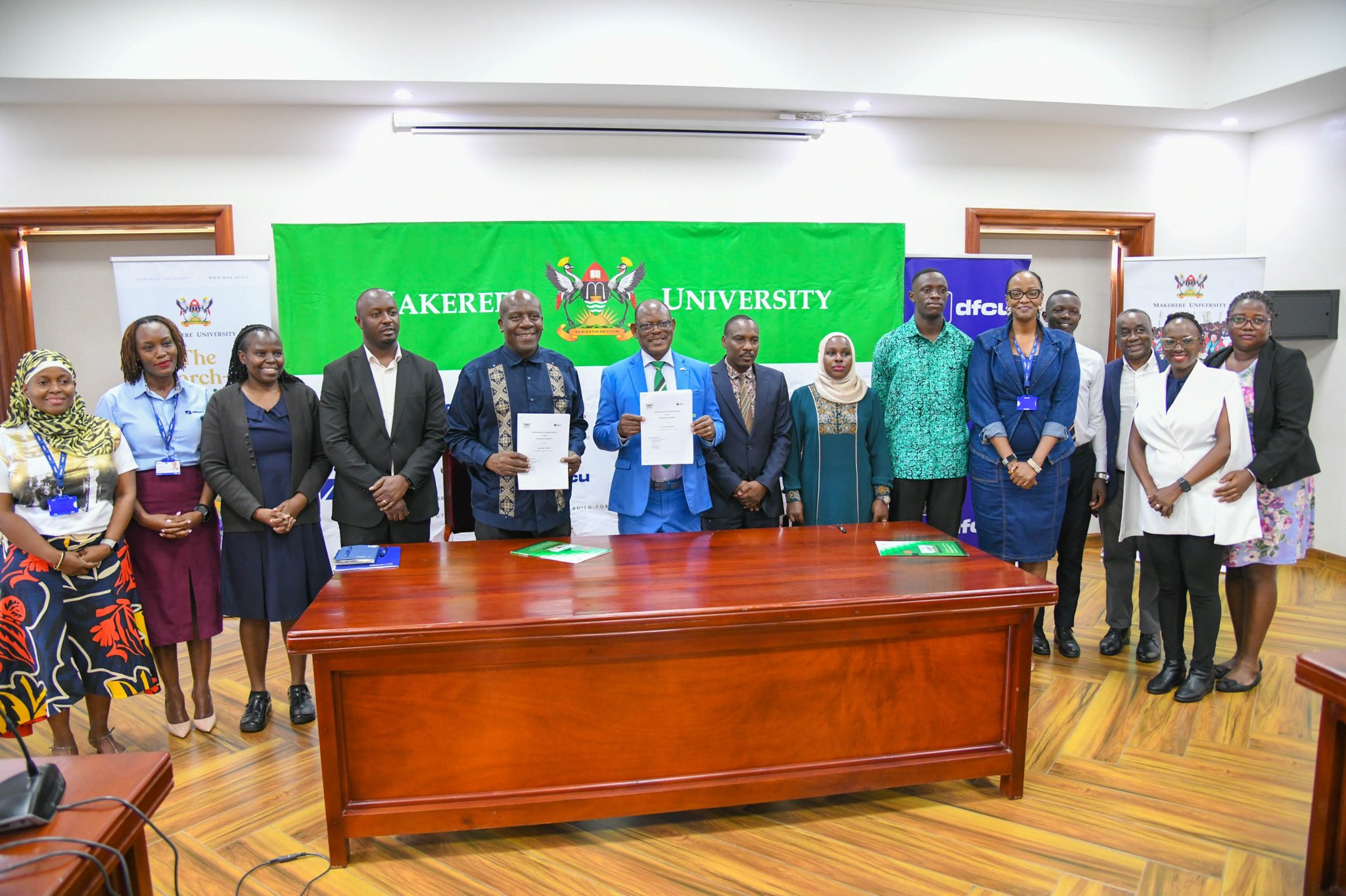 Vice Chancellor, Prof. Barnabas Nawangwe with Managing Director DFCU, Mr. Charles Mudiwaa holding the MoU in witness of other officials