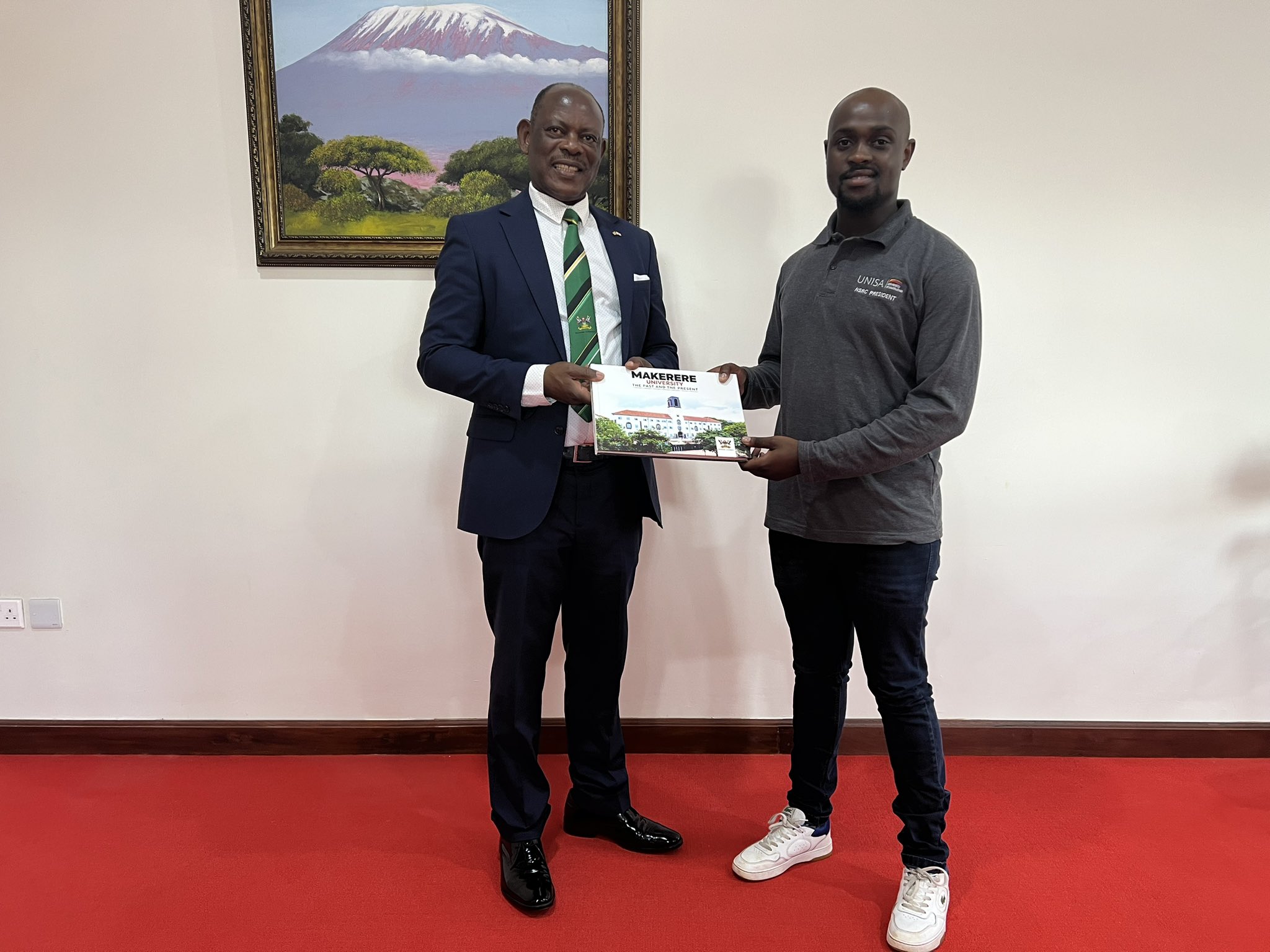 The Vice Chancellor, Prof. Barnabas Nawangwe (L) handing a gift to the Guild President from the University of South Africa (R) during their benchmarking at Makerere University.