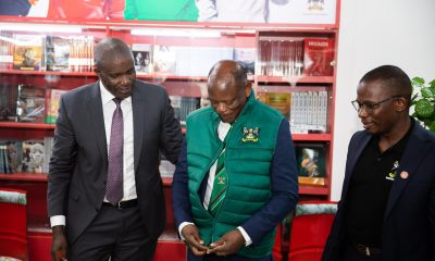 The Vice Chancellor, Prof Barnabas Nawangwe (C) trying on one of the items from the souvenir shop at Makerere University.