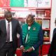 The Vice Chancellor, Prof Barnabas Nawangwe (C) trying on one of the items from the souvenir shop at Makerere University.