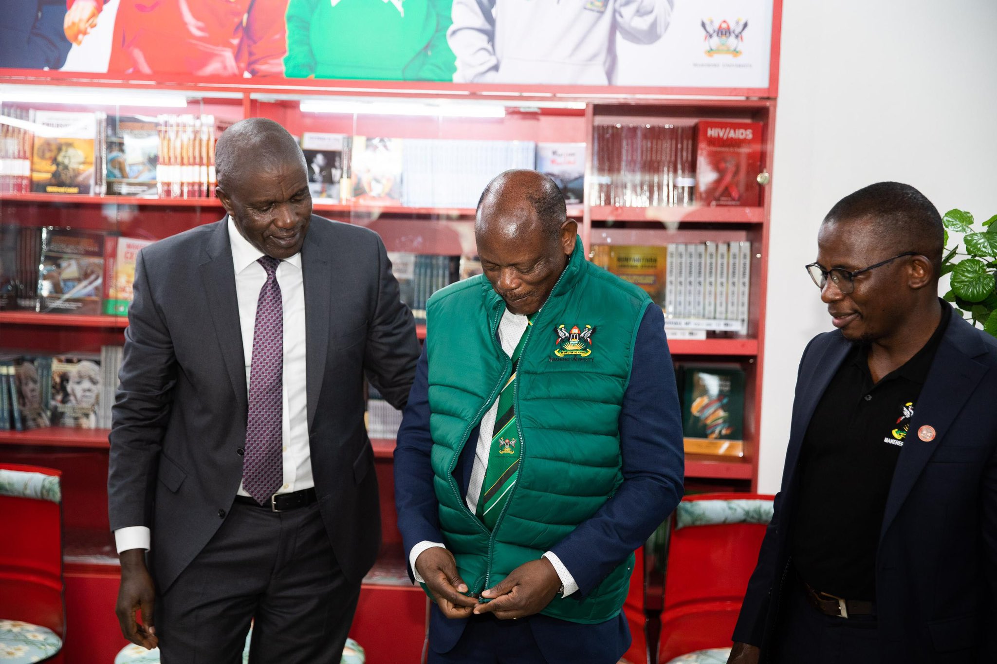 The Vice Chancellor, Prof Barnabas Nawangwe (C) trying on one of the items from the souvenir shop at Makerere University.