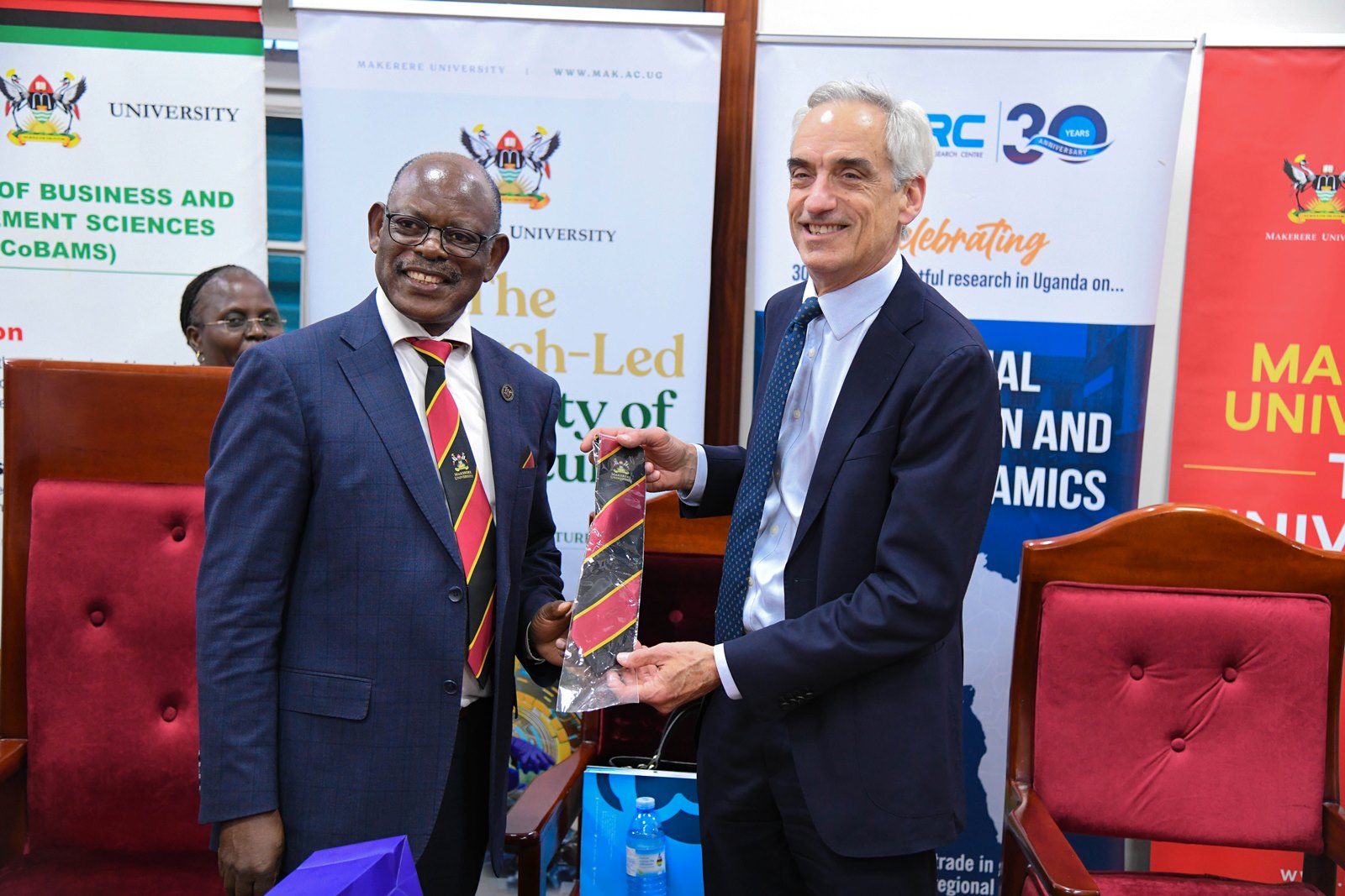 Prof. Nawangwe presents a souvenir Mak Necktie to Dr. Jonathan Leape. Makerere University, through the College of Business and Management Sciences (CoBAMS) and the Economic Policy Research Centre (EPRC), has signed an open Memorandum of Understanding (MoU) with the London School of Economics and Political Science (LSE), 27th August 2025, Kampala Uganda, East Africa.