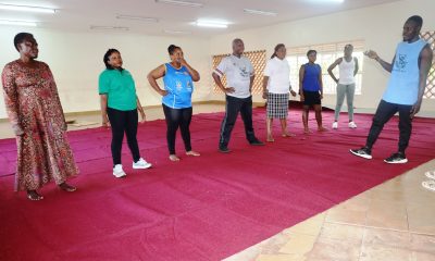 Participants follow instructions during a fitness and wellness session led by a trainer, as part of a health awareness initiative for staff at CoBAMS. Deputy Principal, Associate Professor James Wokadala launches College of Business and Management Sciences (CoBAMS) physical fitness program to promote wellness, better health, team work and cohesion, 17th July 2025, Makerere University, Kampala Uganda, East Africa.