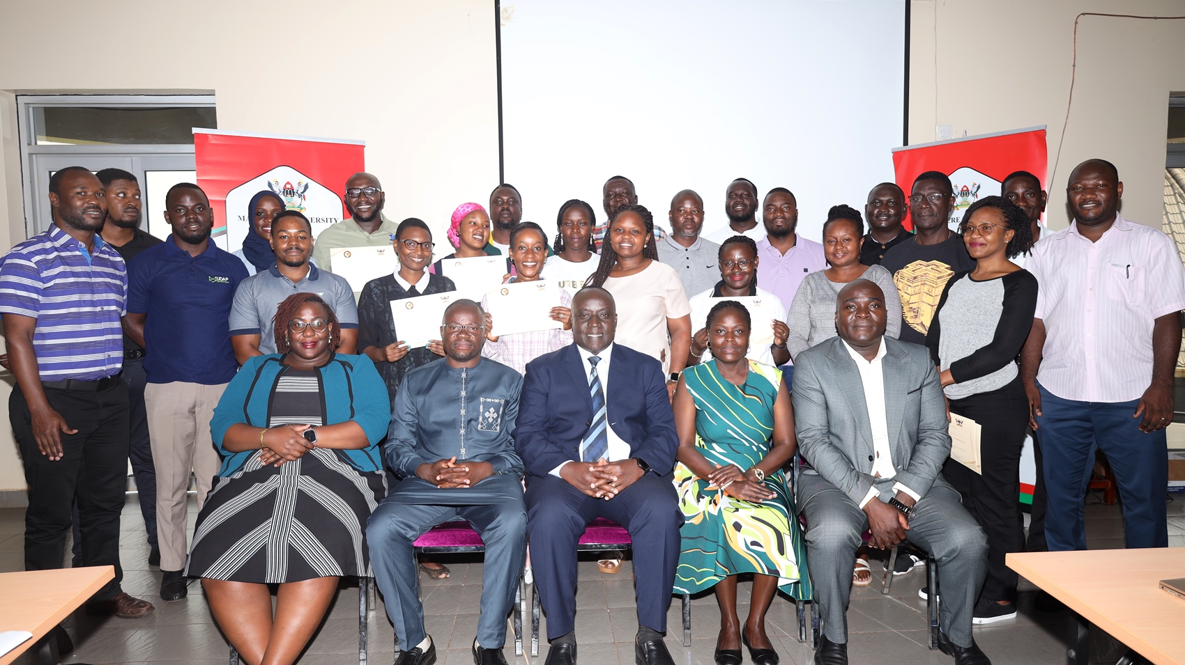 Seated: Mr. Paul Mwanja (Centre), Prof. Ibrahim Mike Okumu (2nd Left) and Dr. John Sseruyange (Right) with trainers at participants in Jinja on 5th September 2025. Ministry of Finance, Planning and Economic Development (MoFPED), in partnership with the Public Investment Management Centre of Excellence (PIM CoE), Makerere University, Kampala, successful completion of two-week intensive training in the Certificate of Financial Implications (CFI) – Integrated Regulatory Cost-Benefit Analysis. September 5 2025, Pearl on the Nile Hotel, Jinja, Uganda, East Africa.