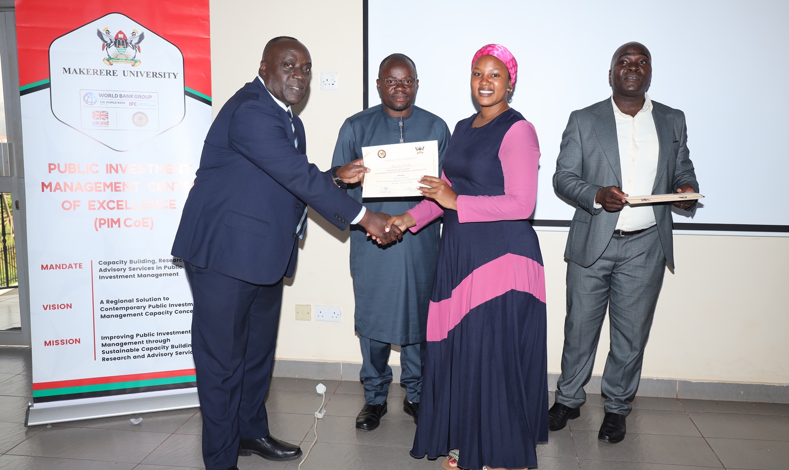 A female participant receives her certificate. Ministry of Finance, Planning and Economic Development (MoFPED), in partnership with the Public Investment Management Centre of Excellence (PIM CoE), Makerere University, Kampala, successful completion of two-week intensive training in the Certificate of Financial Implications (CFI) – Integrated Regulatory Cost-Benefit Analysis. September 5 2025, Pearl on the Nile Hotel, Jinja, Uganda, East Africa.