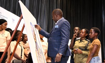 Mr. Yusuf Kiranda autographs the memorial art piece as Mrs. Pamela Kabaasa (2nd Right), her children and members of Hadithi Ya Mzizi witness on 29th August 2025. 3rd edition of Hadithi Ya Mzizi to celebrate the resilience and innovation of the informal sector through art exhibition and to memorialize its founder, the late Nshuti Balaam Kabaasa, 29th August 2025 Makerere University, Kampala Uganda, East Africa.