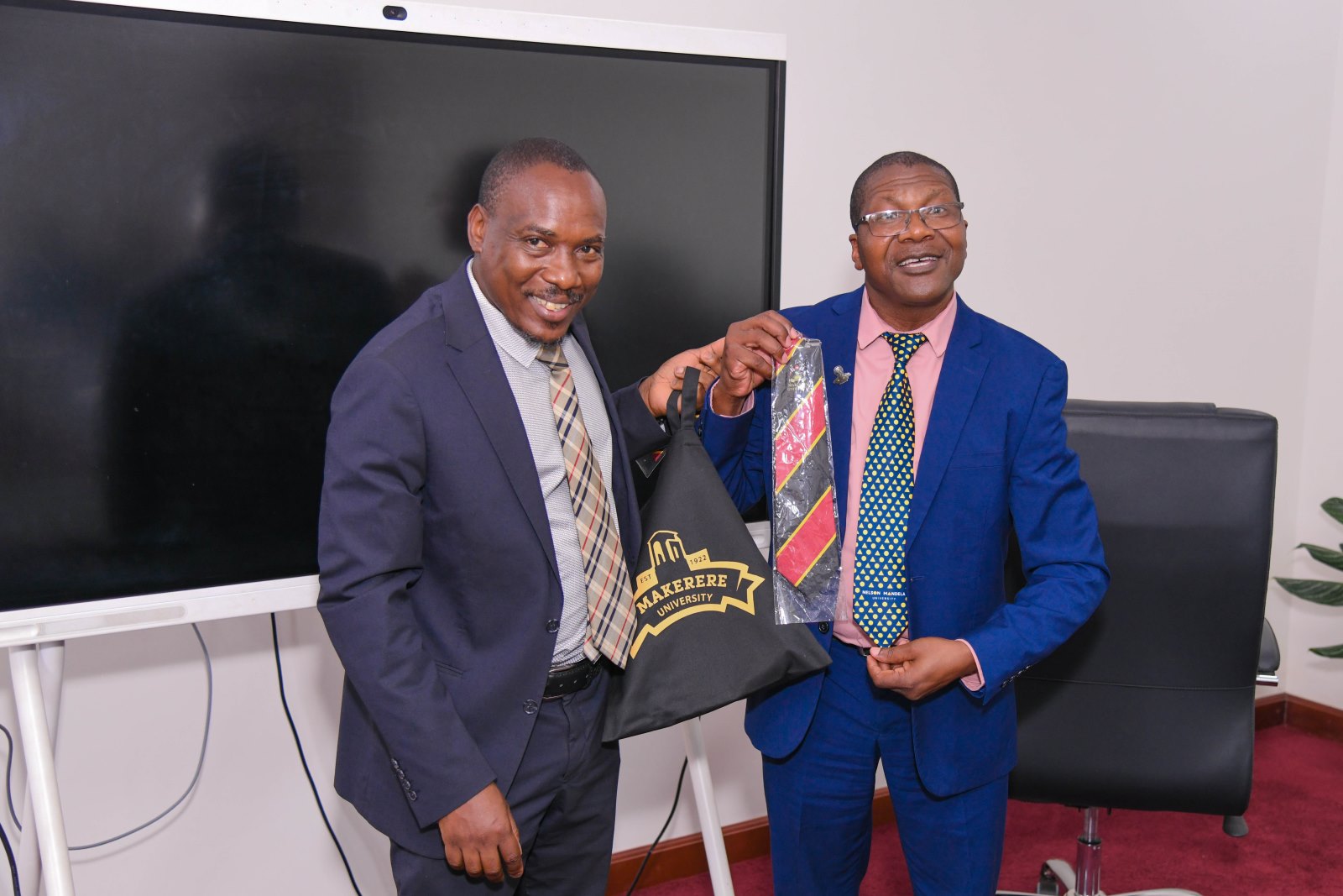 Prof. Winston Tumps Ireeta (L) presents a Mak necktie to Prof. Azwinndini Muronga (R). Delegation from Nelson Mandela University (NMU), South Africa meeting with officials from Makerere University on 7th October 2025, Kampala Uganda, East Africa.