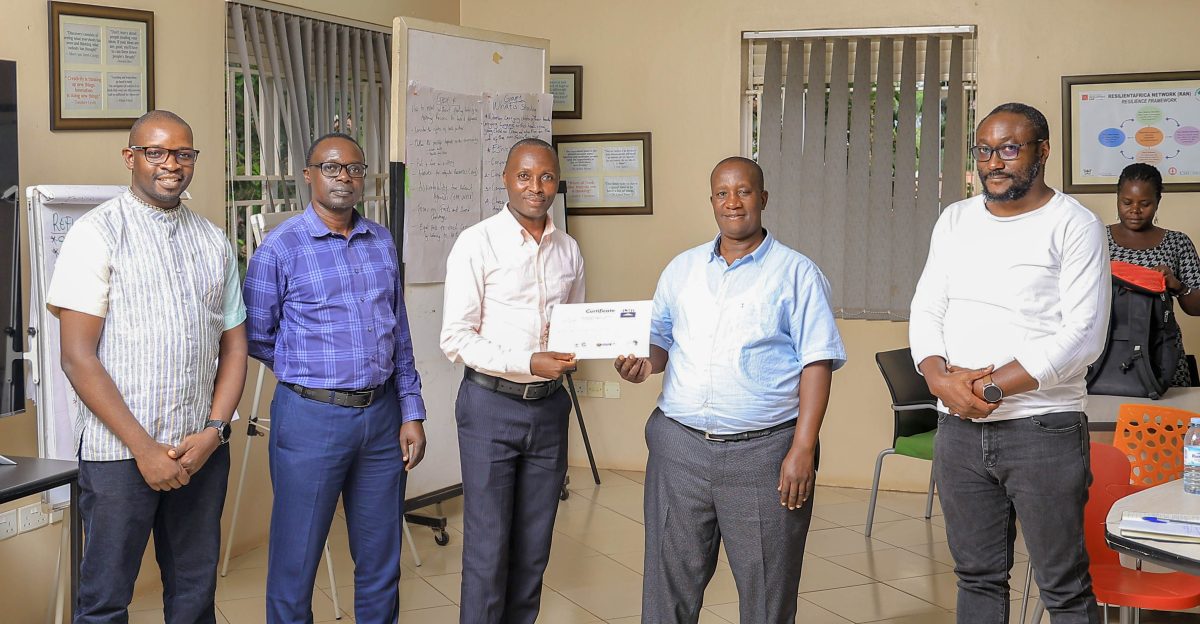 From right: Africa Humanitarian Action’s Mr. Yakobo Kaheesi and Emesco Development Foundation’s Mr. Patrick Ssentalo join facilitators and organisers Mr. Wilson Akiiki Kaija and Mr. Davidson Ndyabahika in awarding certificates to media participants after the successful training on Refugee Health and Migration Reporting on October 3, 2025. Media Training Workshop on Refugee Health and Migration Reporting that brought together twenty journalists from Kampala, Kyaka II, Adjumani, and other refugee-hosting districts, Makerere University School of Public Health (MakSPH), Kampala Uganda, East Africa on 3rd October 2025.