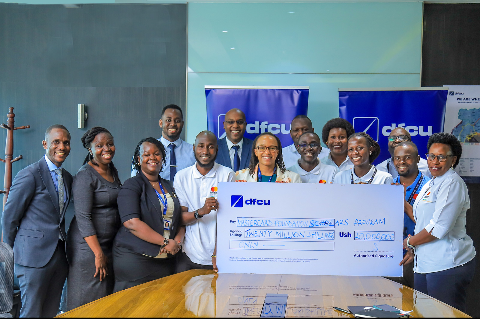 The officials of DFCU Bank and the Scholars Program staff pose in a photo with the 20 Million Shillings dummy cheque donation by DFCU Bank.