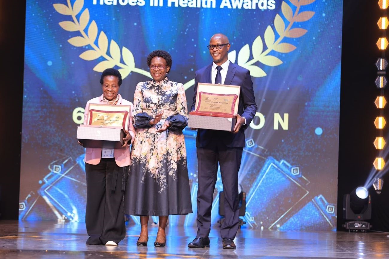 Staff from the Makerere University College of Health Sciences (MakCHS) recognised for their contribution to the health sector in Uganda and beyond during 6th edition of the Heroes in Health Awards (HIHA) held 14th November 2025 during the Africa Health Summit at Kololo Ceremonial Grounds, Kampala Uganda, East Africa. Professor Moses Galukande (Right) and Dr. Mary Nabbosa (Left) with Hon. Dr. Jane Ruth Aceng (Centre) after receiving their respective Minister’s Special Recognition Awards.