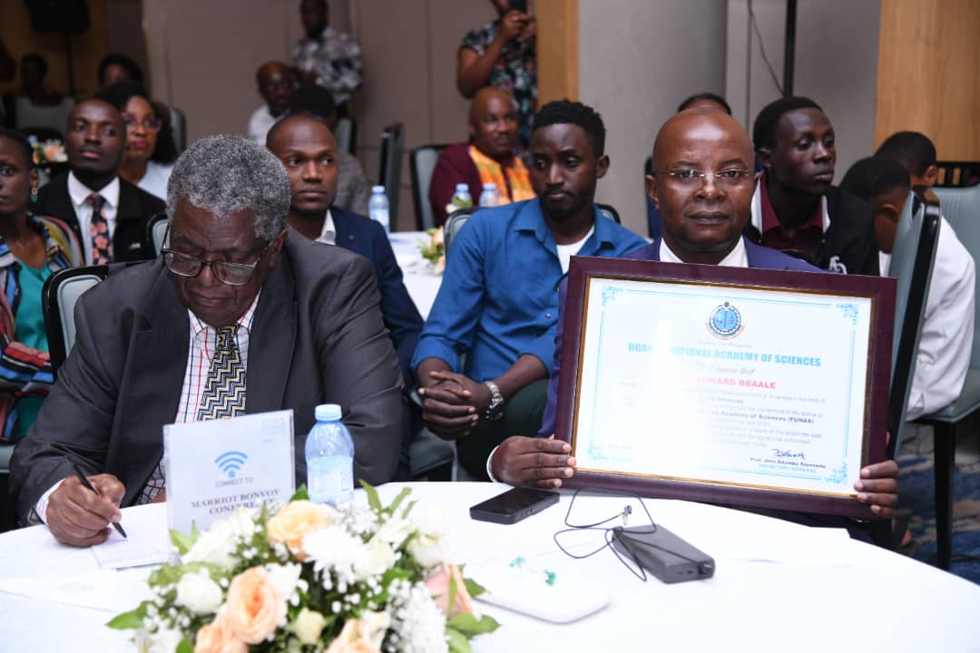 Prof. Bbaale shows off his UNAS certificate. To his left is Prof. David Bakibinga, FUNAS. Professor Edward Bbaale, Principal of the College of Business and Management Sciences (CoBAMS), Makerere University, inducted into the prestigious fellowship of the Uganda National Academy of Sciences (UNAS), 31st October 2025, Kampala Uganda, East Africa.