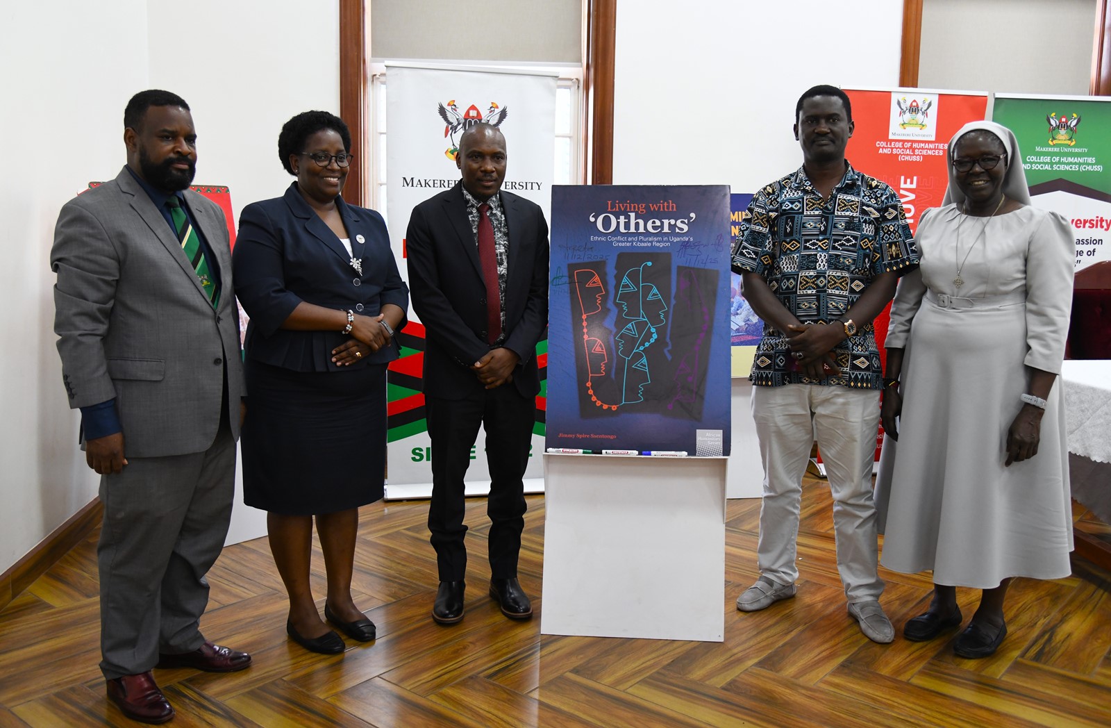 A group photo with the "Living with Others: Ethnic Conflict and Pluralism in Uganda's Greater Kibaale Region" book dummy. College of Humanities and Social Sciences (CHUSS) on 11th December 2025 celebrated the launch of five scholarly books, marking a significant milestone in the College’s contribution to academic research and discourse, Senior Common Room, Main Building, Makerere University, Kampala Uganda, East Africa.
