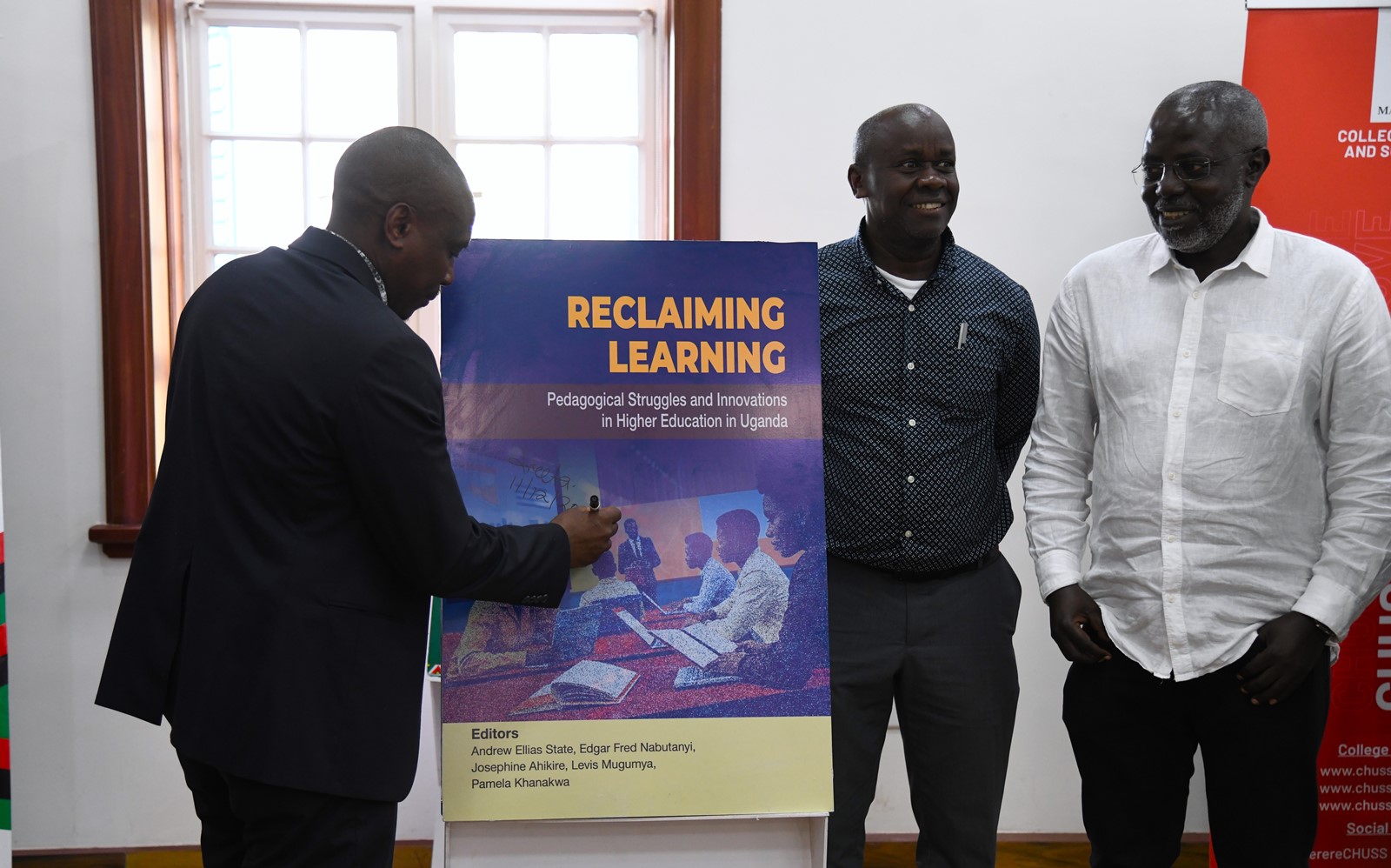 Prof. Winston Tumps Ireeta autographs the "Reclaiming Learning" book dummy. College of Humanities and Social Sciences (CHUSS) on 11th December 2025 celebrated the launch of five scholarly books, marking a significant milestone in the College’s contribution to academic research and discourse, Senior Common Room, Main Building, Makerere University, Kampala Uganda, East Africa.