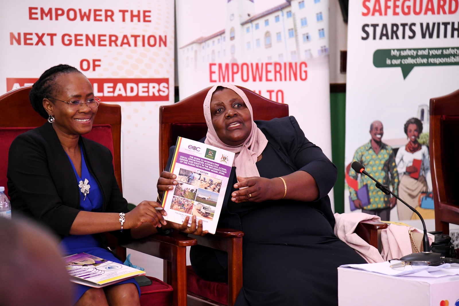 Hon. Safia Nalule Jjuuko (Right) presents a copy of "The Guide to Integrating Equal Opportunities Affirmative Action, Gender and Equity in the Implementation of the Parish Development Model (PDM)" to Prof. Sarah Ssali (Left) during her keynote address. Makerere University International Day of Persons with Disabilities Celebration, a moment dedicated to reflection on inclusion and shared responsibility organised by the Dean of Students and 91st Guild Ministry of Students with Disabilities, 1st December 2025, Main Hall, Kampala Uganda, East Africa.