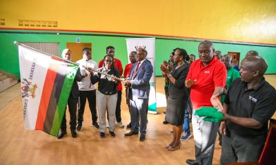 Prof. Barnabas Nawangwe hands the Makerere flag over to Team Captain-Namutebi Rhonah Majoline as Dr. Winifred Kabumbuli (3rd Right), Mr. Brian Miiro (2nd Right) and Left to Right: Dr. Rodney Rugyema, Phillip Nuwagaba, Katsirabo Donic, Akampa Bob James and others applaud on 17th December 2025 in the Mak Indoor Sports Arena. Prof. Barnabas Nawangwe officially flags off a contingent of 220 students, 13 coaches and 3 tutors from the Makerere University Games Union on 17th December 2025 at the Indoor Sports Arena to the 20th Edition of the Association of Uganda University Sports (AUUS) Games, 18th-23rd December 2025, Uganda Christian University (UCU) Mukono, Uganda, East Africa.