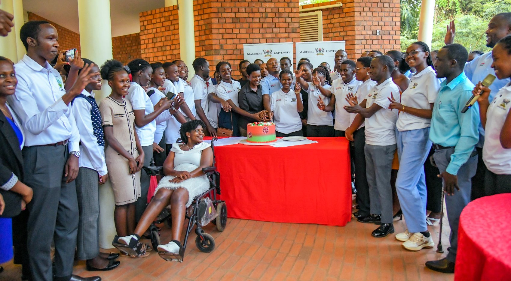 Dr. Rodney Rugyema (Centre) is joined by Staff and Student Safeguarding Champions to cut cake on 28th November 2025. Makerere University student and staff Safeguarding Champions celebration of Semester One achievements, 28th November 2025, Makerere Institute of Social Research (MISR) Gardens, Kampala Uganda, East Africa.