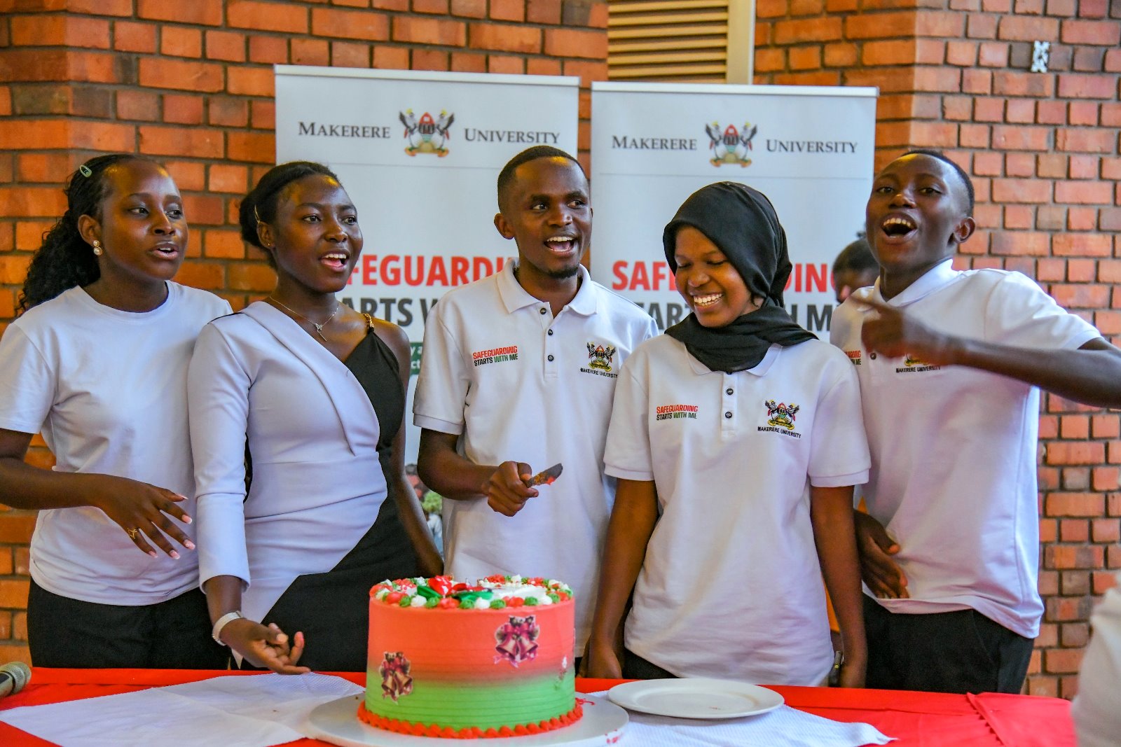 Student Safeguarding Champions prepare to cut cake. Makerere University student and staff Safeguarding Champions celebration of Semester One achievements, 28th November 2025, Makerere Institute of Social Research (MISR) Gardens, Kampala Uganda, East Africa.