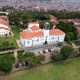 An aerial shot of the Main Building, as taken by a drone over the Freedom Square with Left to Right: CHUSS, St. Francis, St. Augustine and CAES Buildings and the Kikoni area (Background) in view. Makerere University, Kampala Uganda, East Africa.